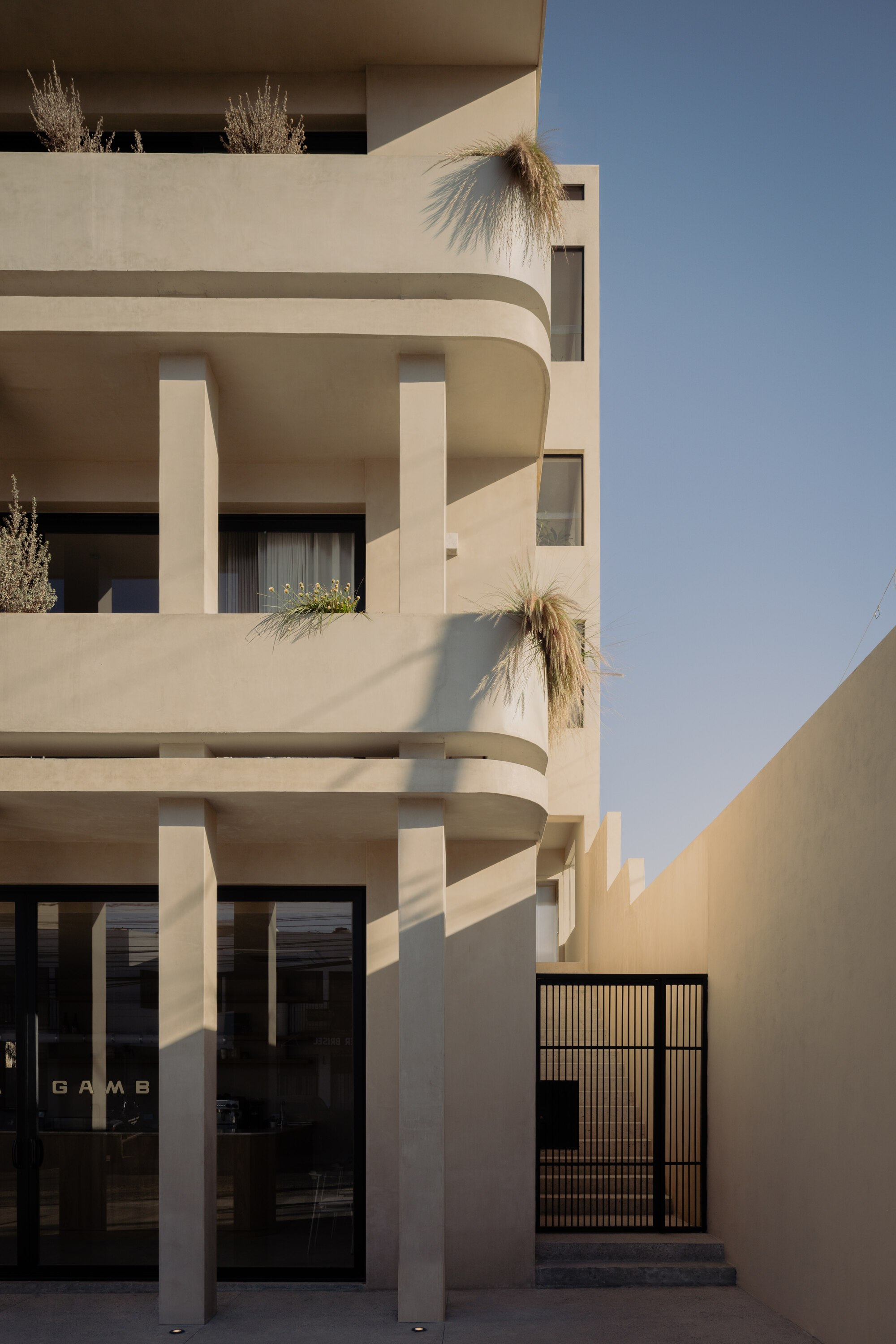 Close-up of stacked curved balconies with columns and grasses in the afternoon sun