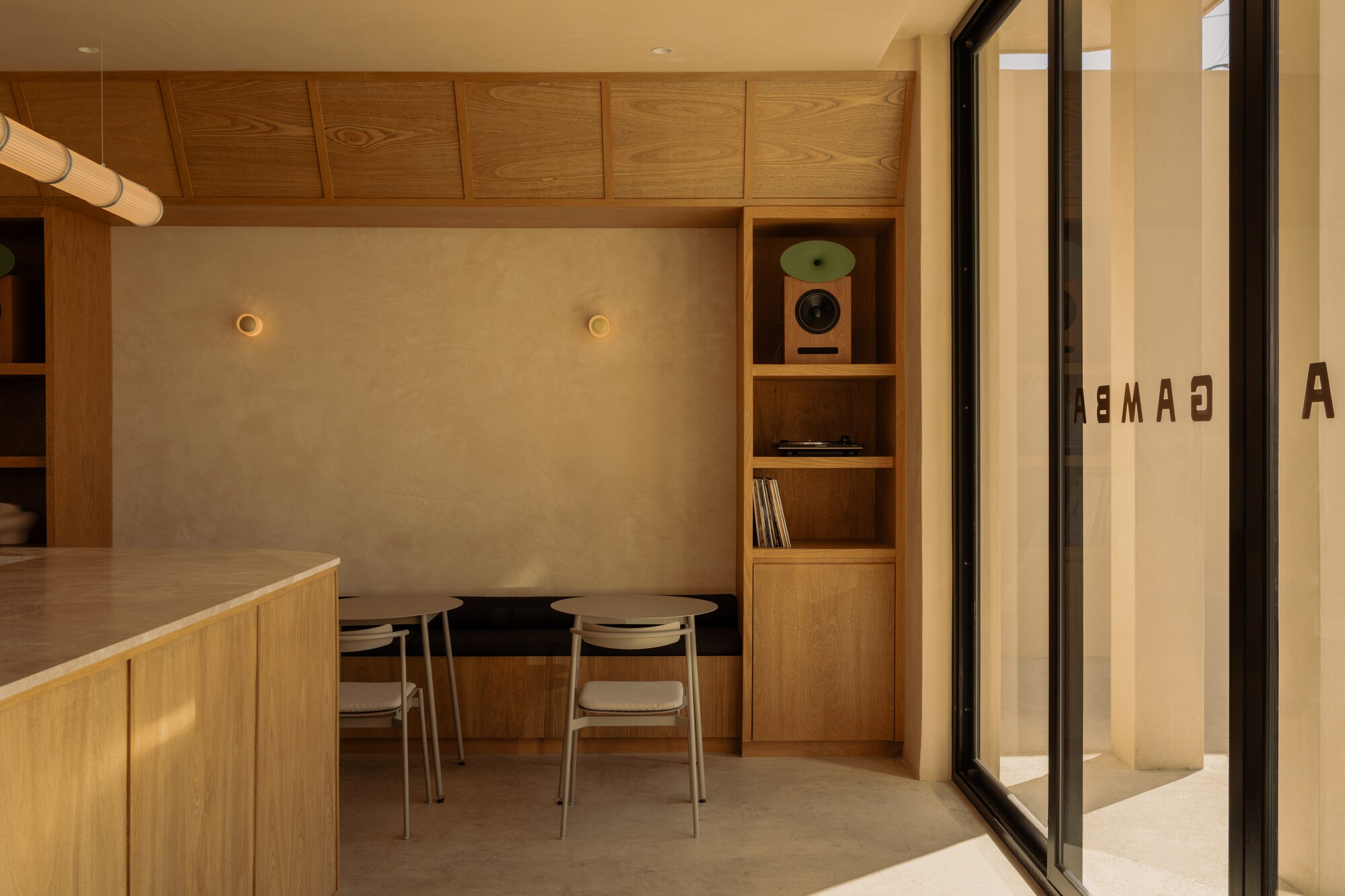 Dining nook with timber ceiling and built-in shelving beneath warm wall sconces