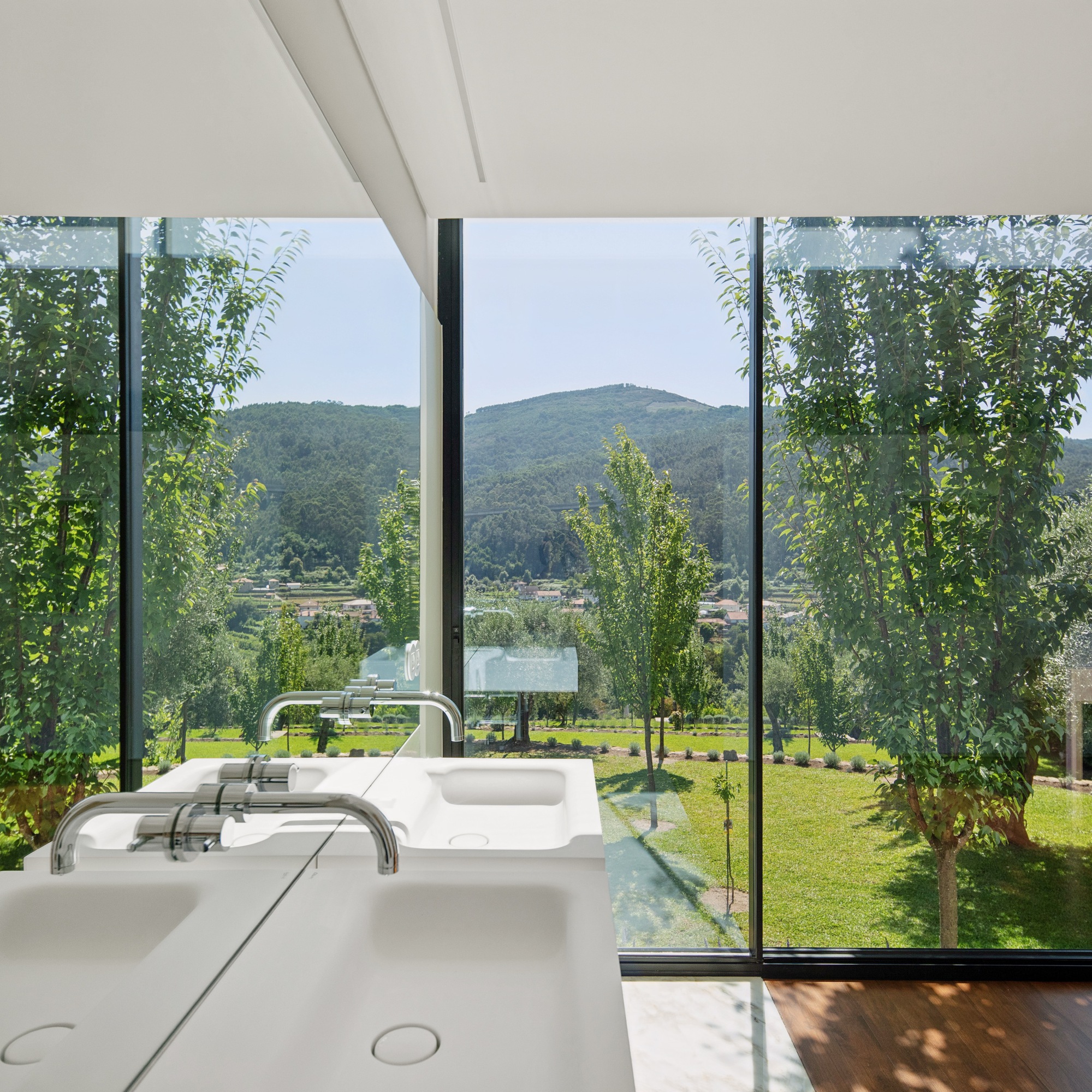 Double basin vanity facing full-height glazing with view to lawn and mountain valley beyond