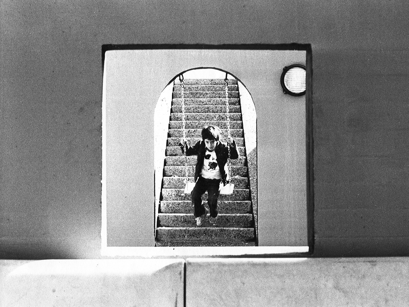 Arched doorway with circular window framing a view of stone steps and a figure descending