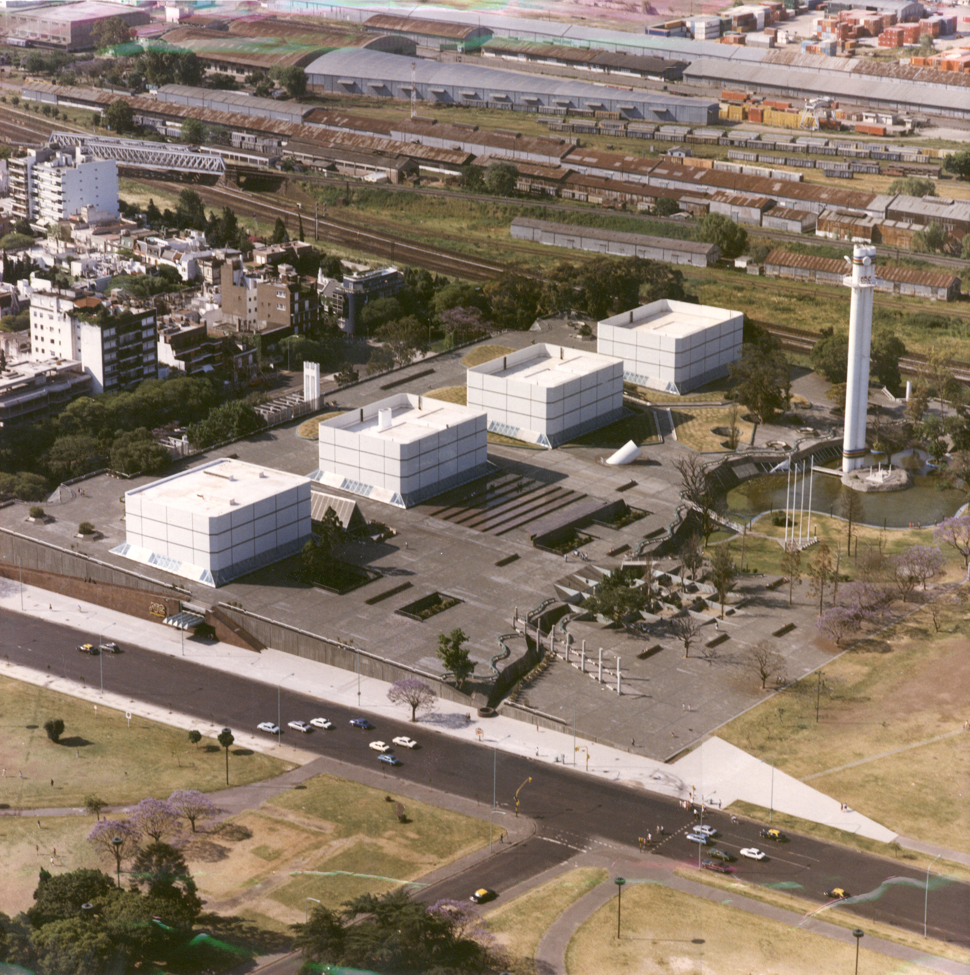 Aerial view of white cubic volumes arranged around a plaza with a cylindrical tower