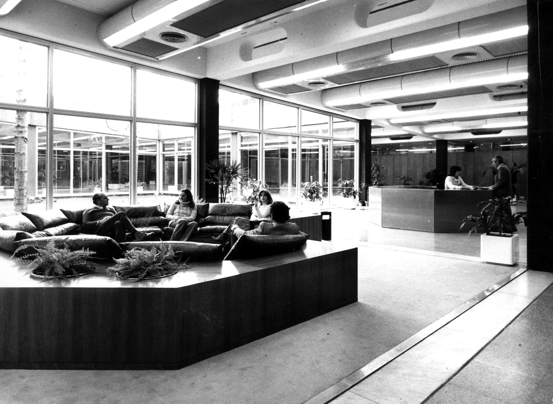 Interior lobby with sunken seating planters and floor-to-ceiling glazing facing a courtyard