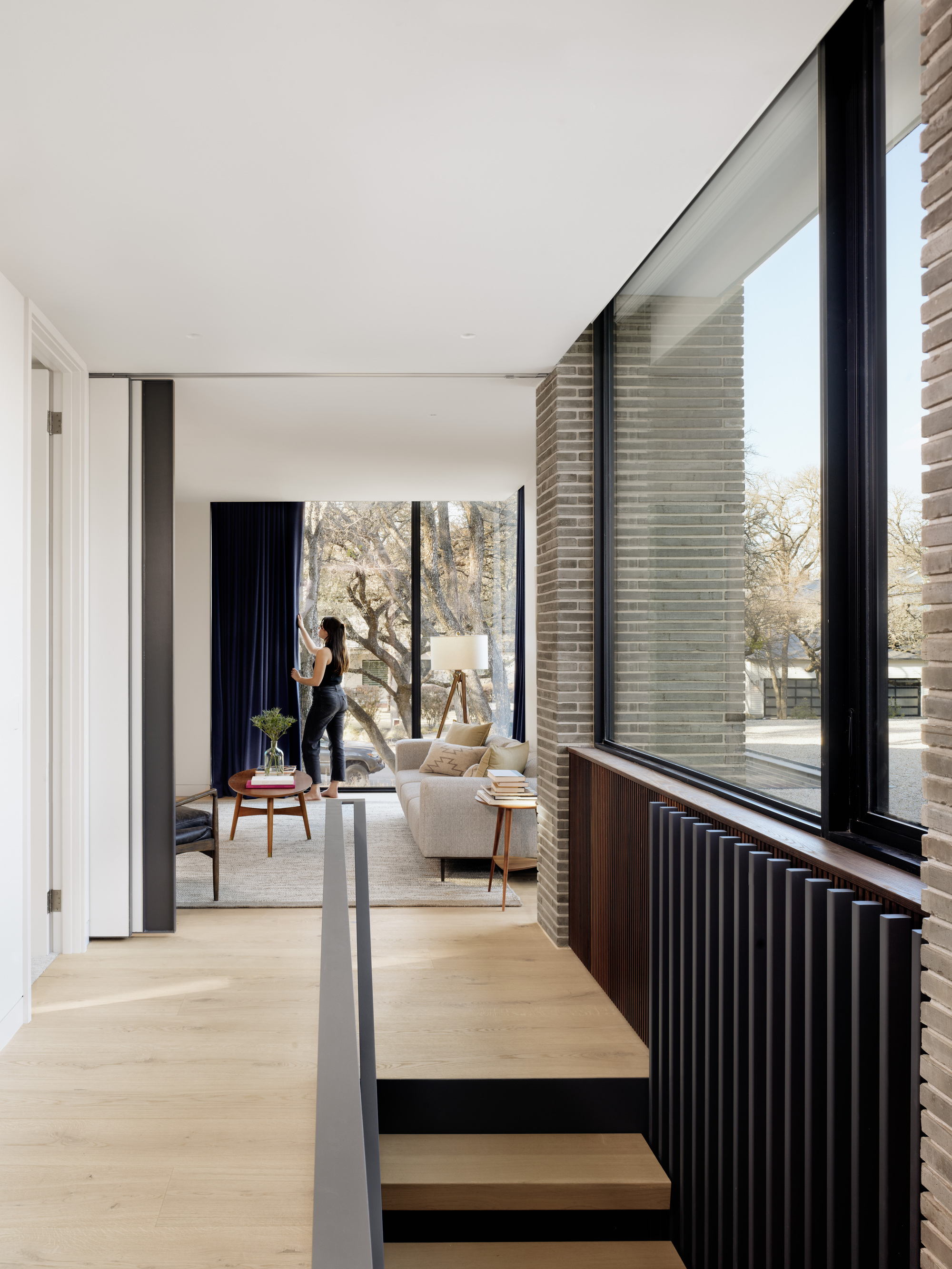 Interior hallway with fluted wood radiator cover below corner windows framing the landscape