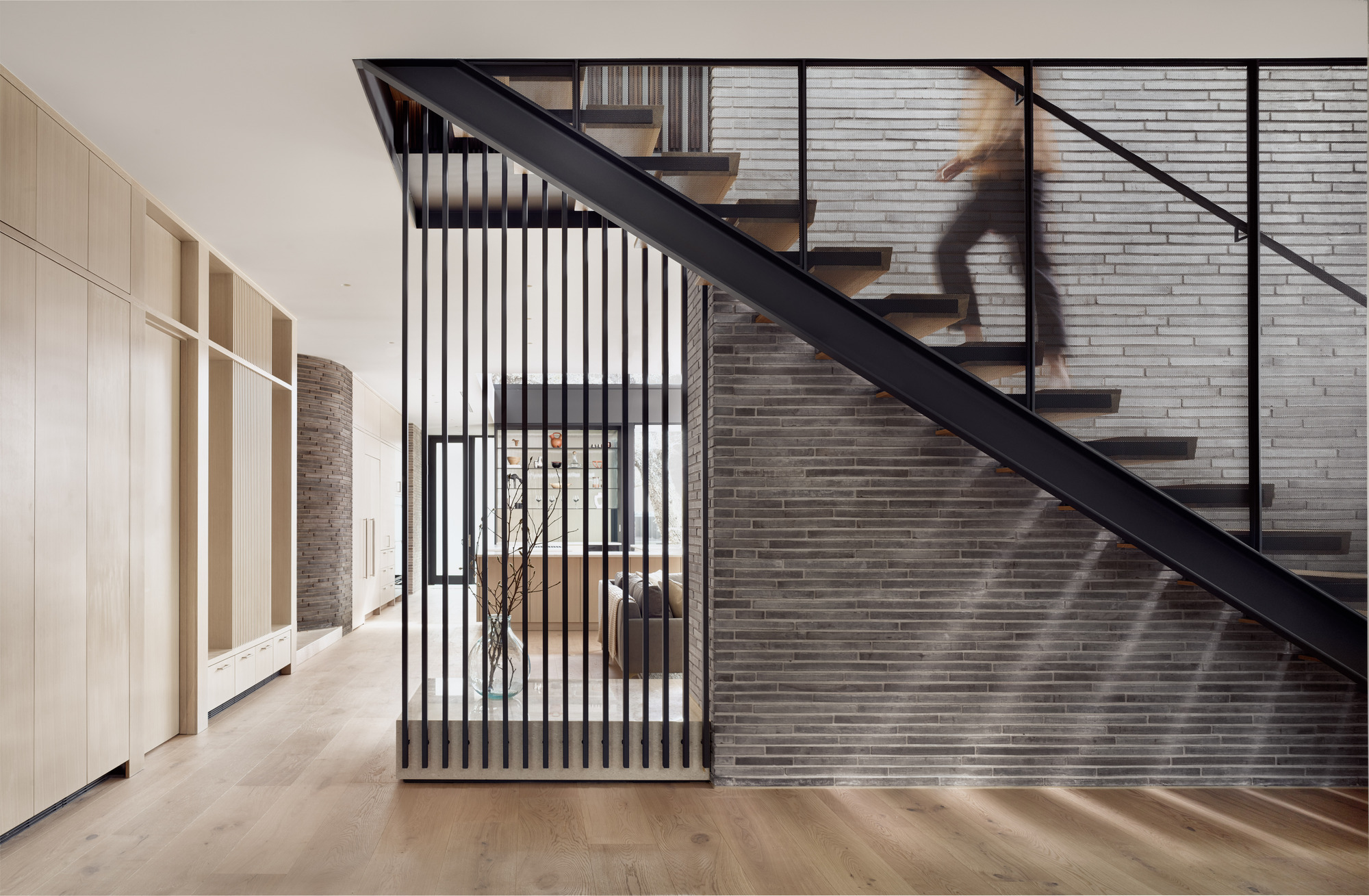 Open-tread staircase with black steel stringer and vertical slat balustrade casting afternoon shadows