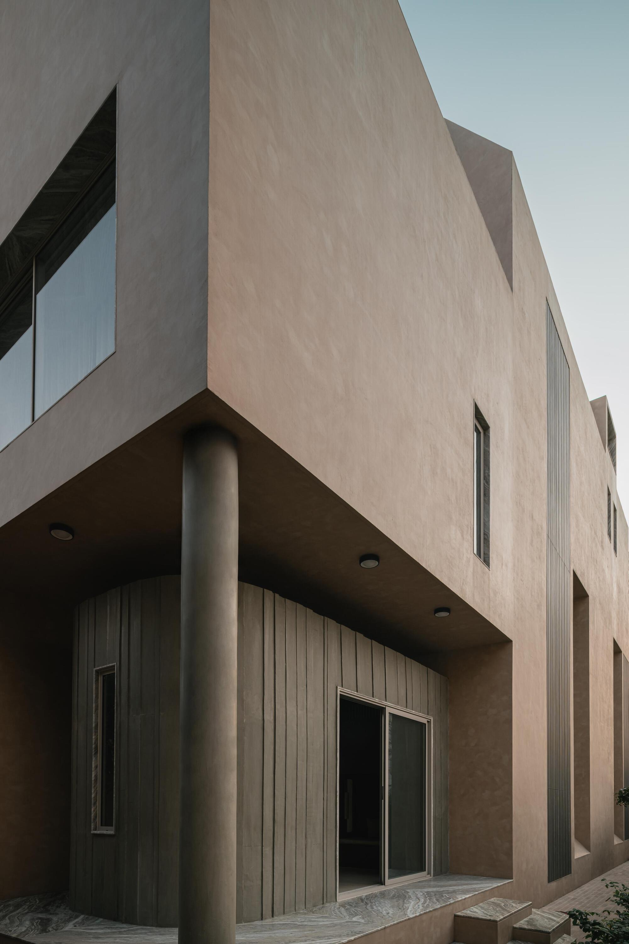 Exterior corner showing cantilevered volumes supported by cylindrical columns and timber cladding