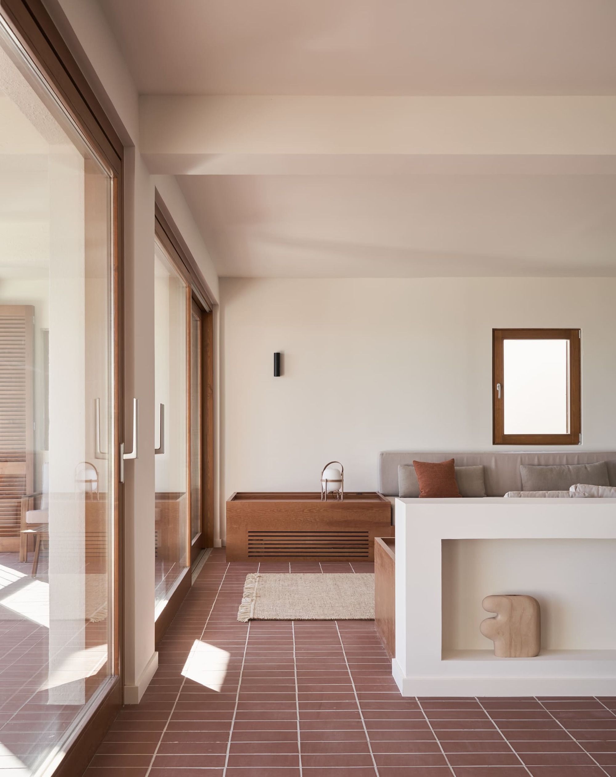 Interior hall with terracotta tile floor and timber kitchen unit bathed in afternoon sunlight