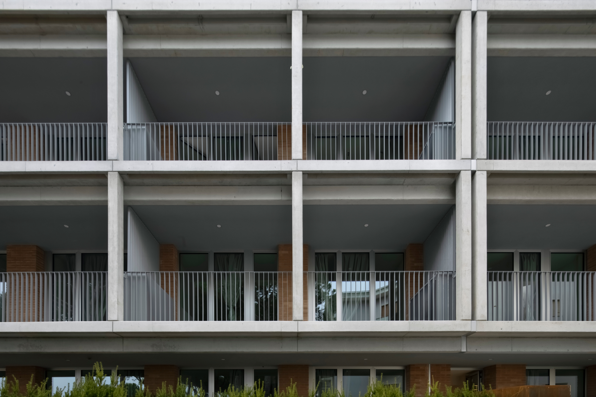 Concrete structural grid facade with recessed balconies lined with vertical timber slats and metal railings