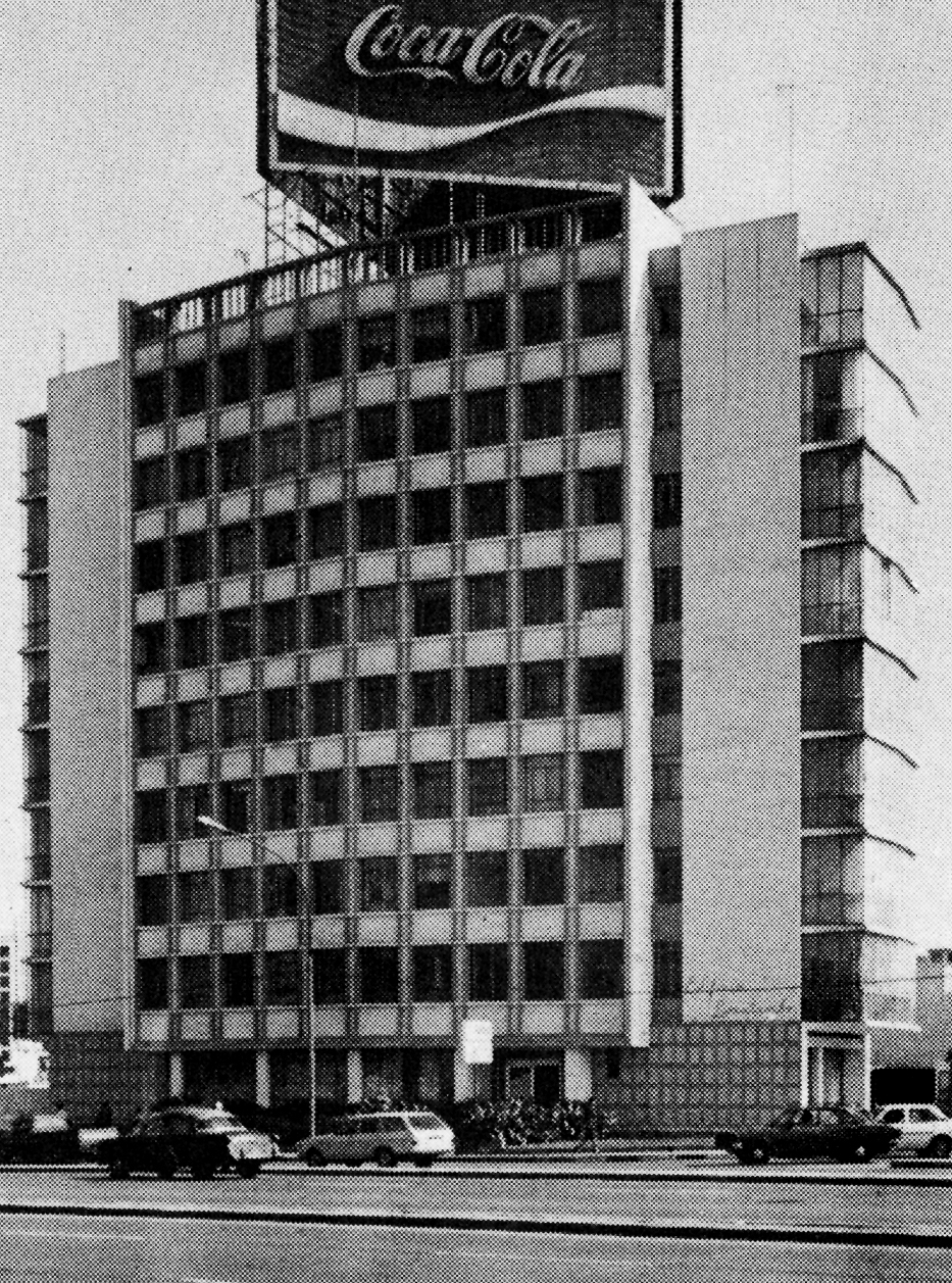 Street view of the chequered glass and panel facade topped with a large billboard sign