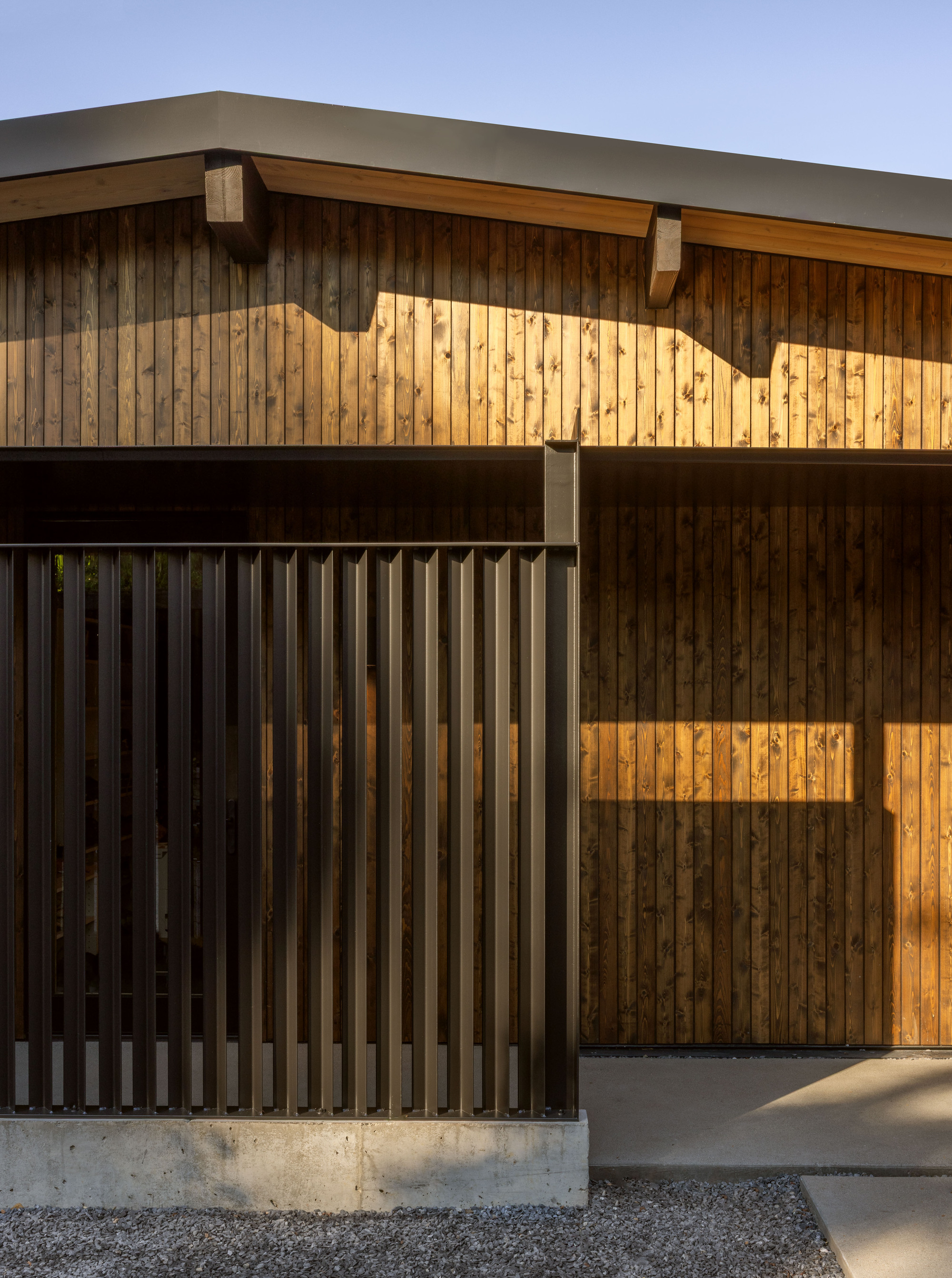 Facade detail of vertical timber cladding with exposed timber brackets supporting the projecting roof overhang