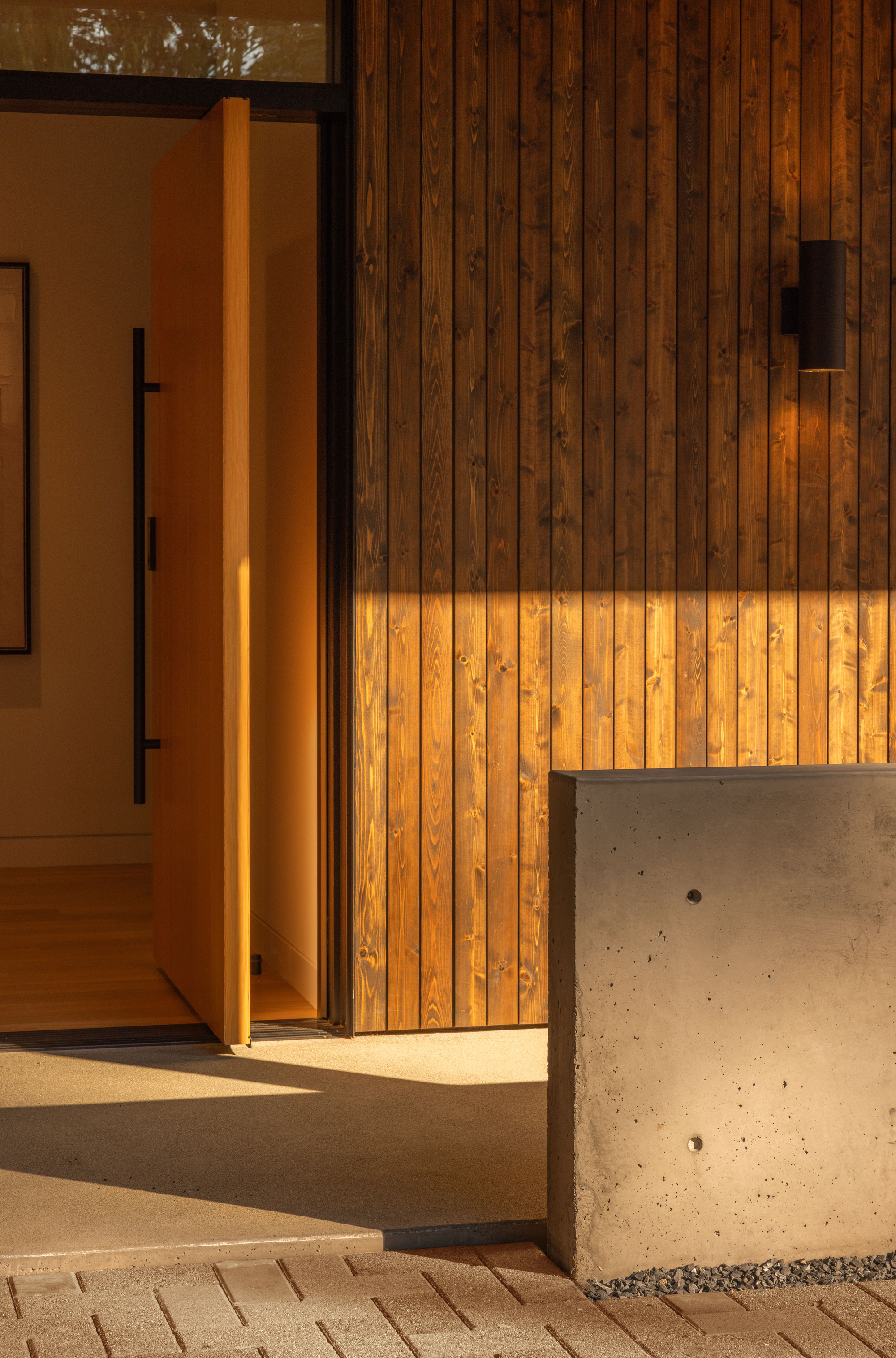 Entry threshold showing timber wall with concealed lighting strip above concrete retaining wall at sunset