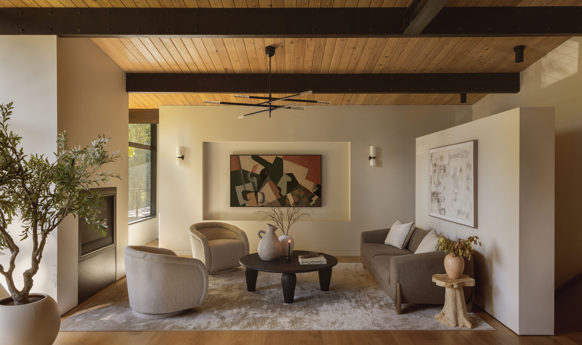 Living room with exposed timber beams and ceiling with potted olive tree beside seating area