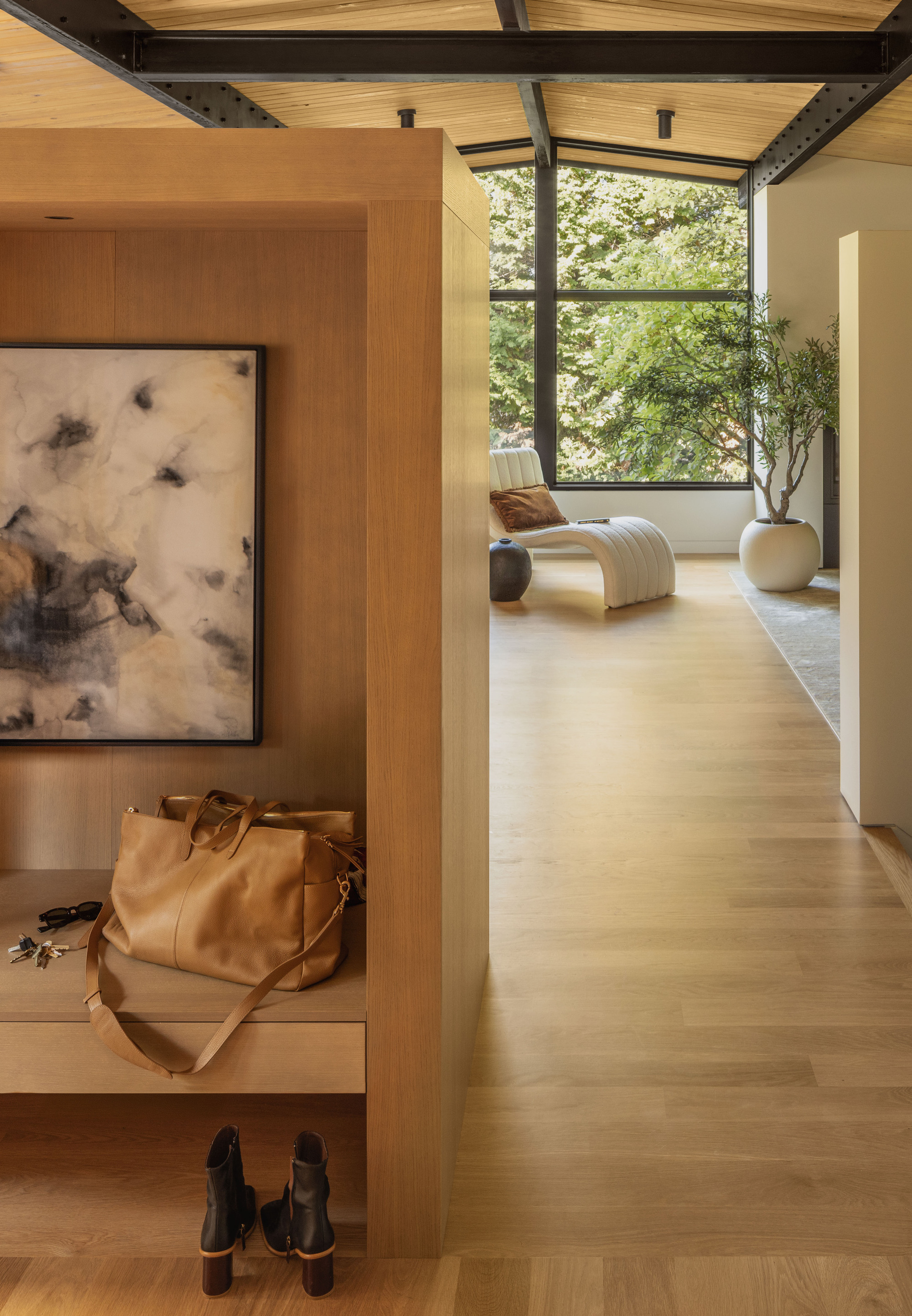 Entry niche with timber storage and framed artwork opening to a daylit hallway beyond