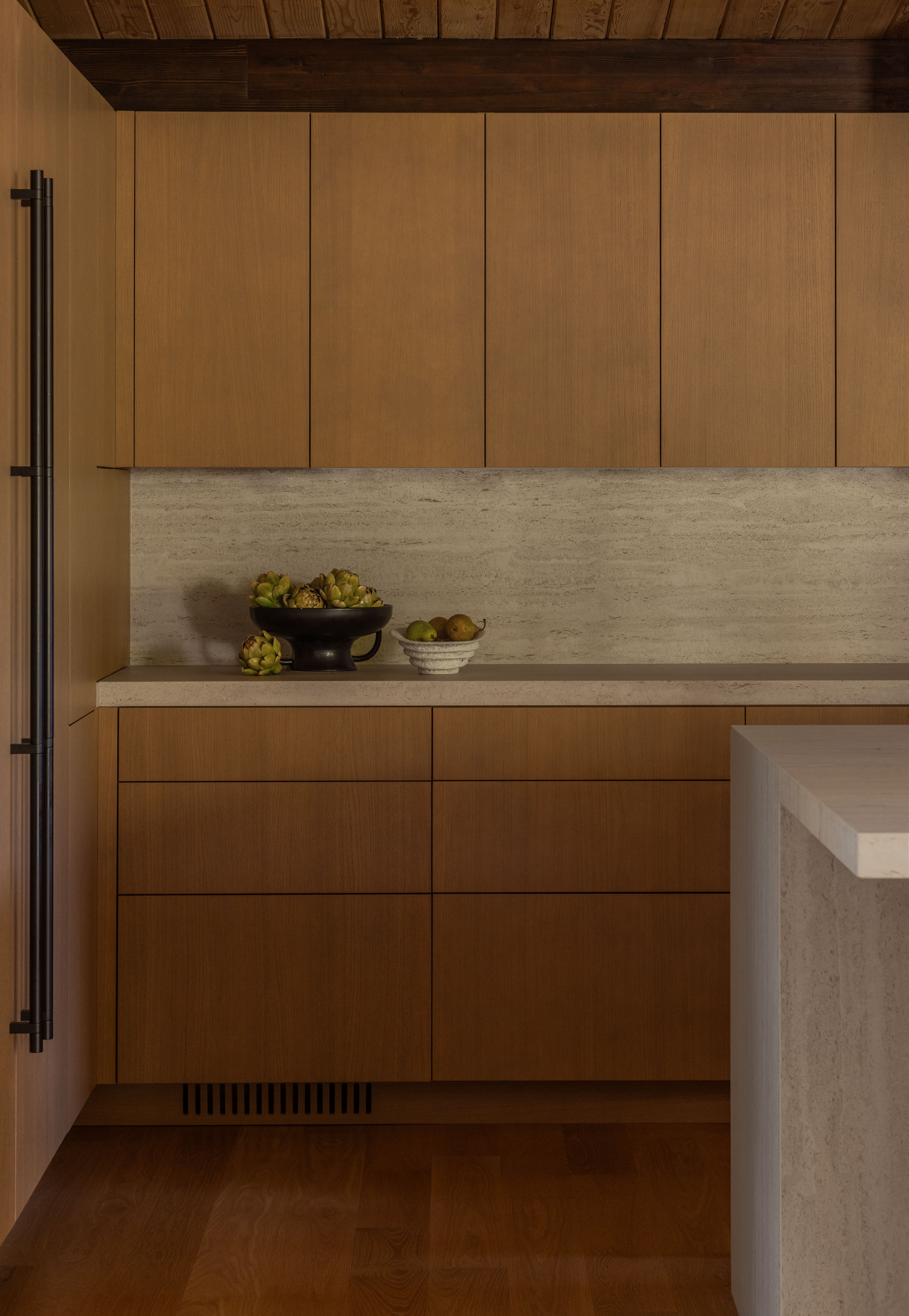 Kitchen counter with horizontal stone slab backsplash and timber cabinetry under wood ceiling