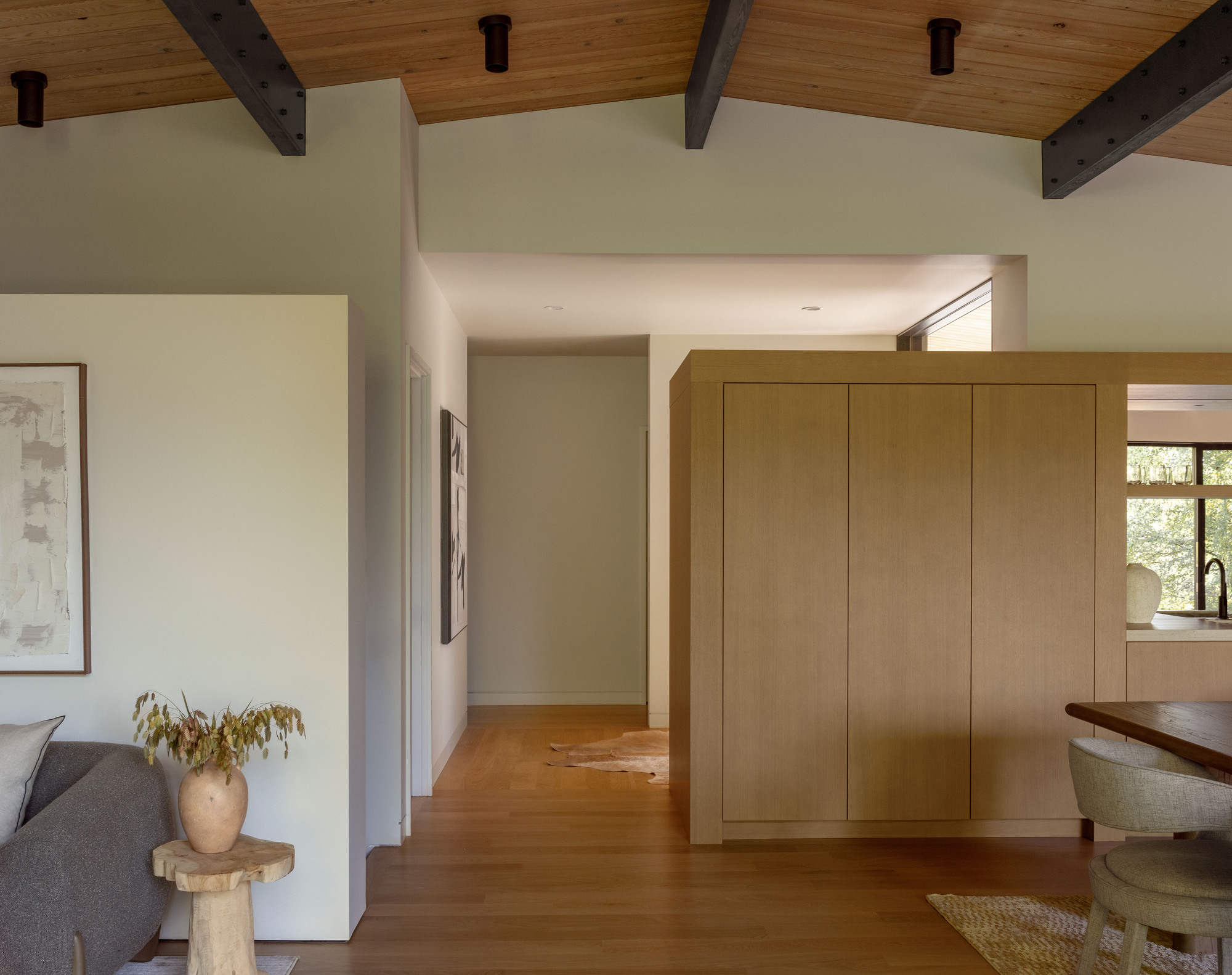 Living space with freestanding timber storage volume connecting to kitchen under exposed ceiling beams