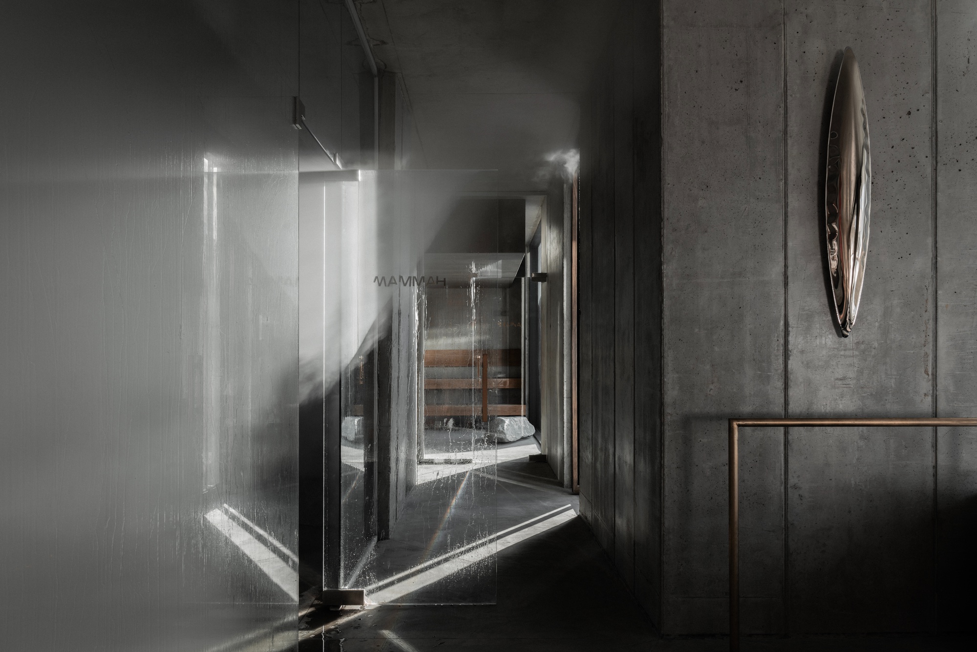 Corridor with glass panels and concrete walls casting angular shadows from overhead track lighting
