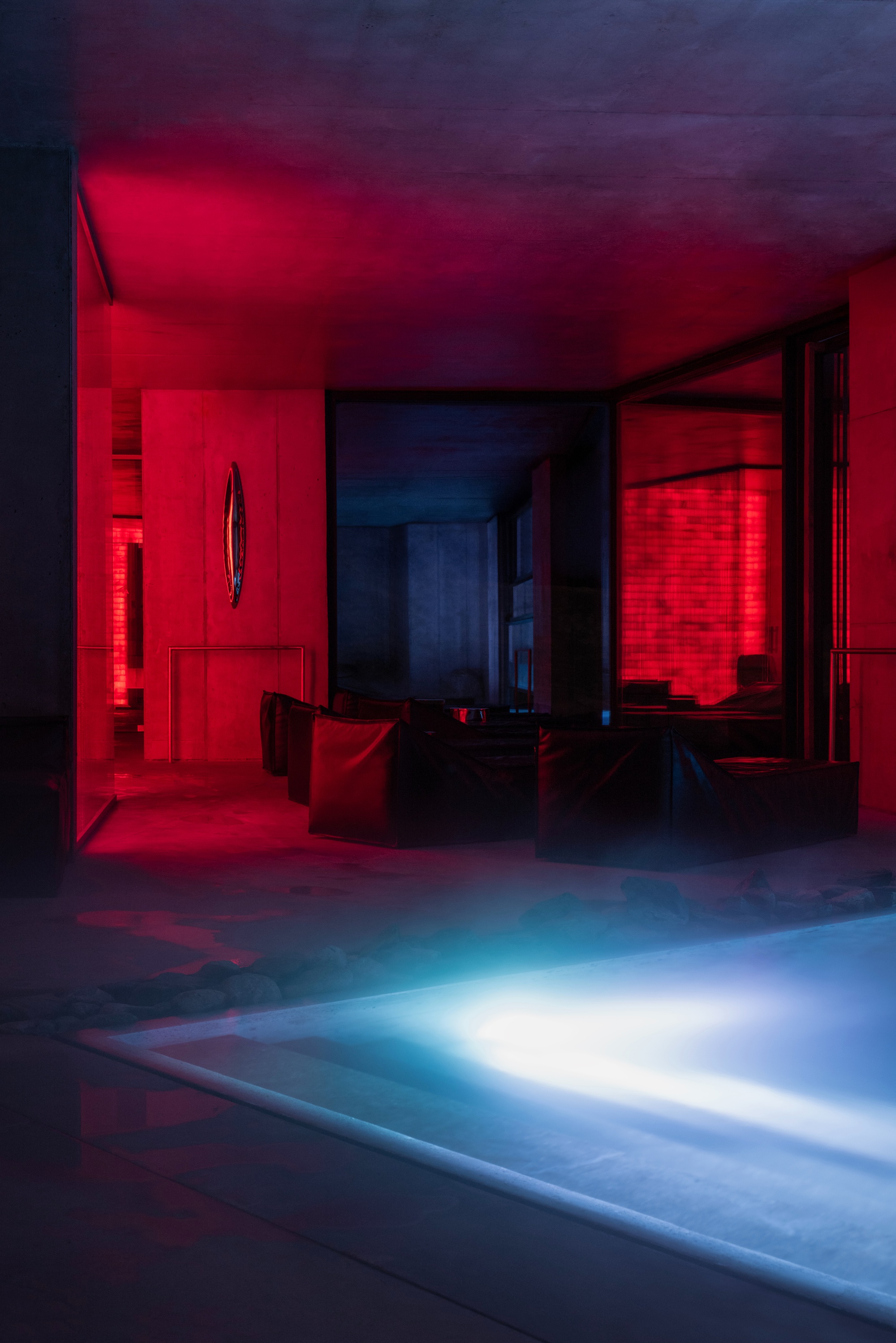 Interior view showing blue-lit pool edge with red and purple ambient lighting in adjacent rooms
