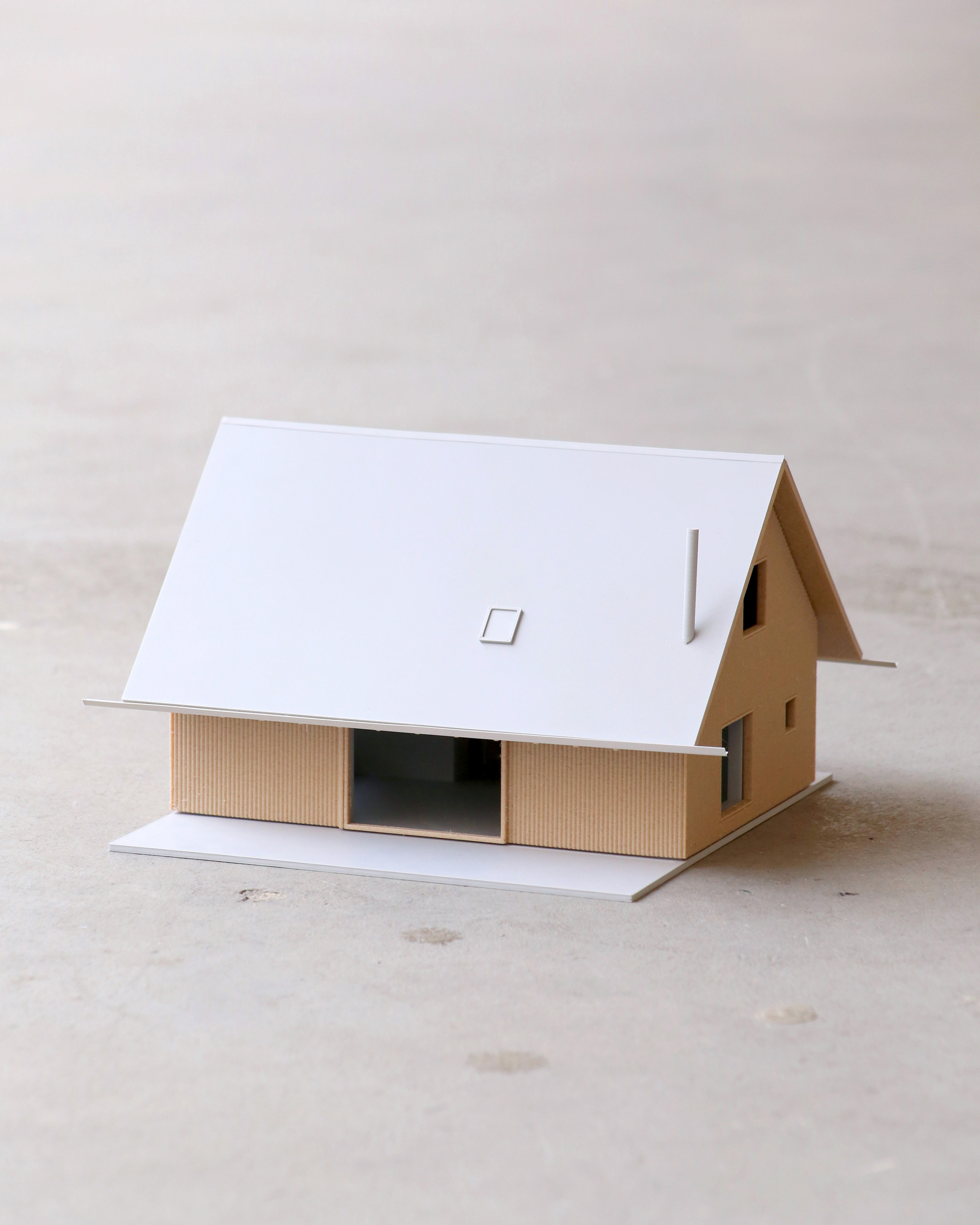 Physical model of the house with gabled roof, vertical timber cladding, and central glazed opening