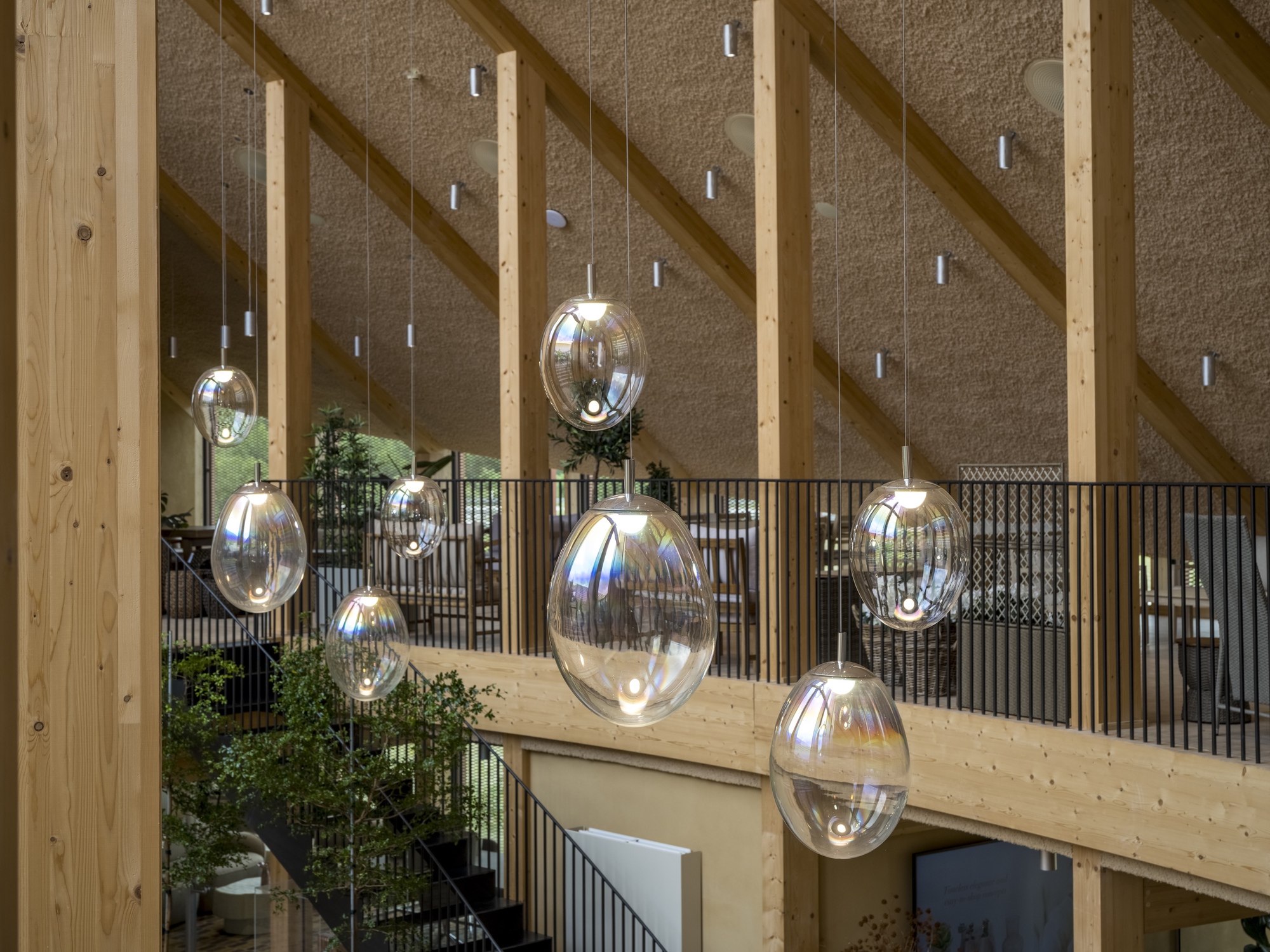 Cluster of oval glass pendant lights suspended from timber beams in front of metal balcony railing
