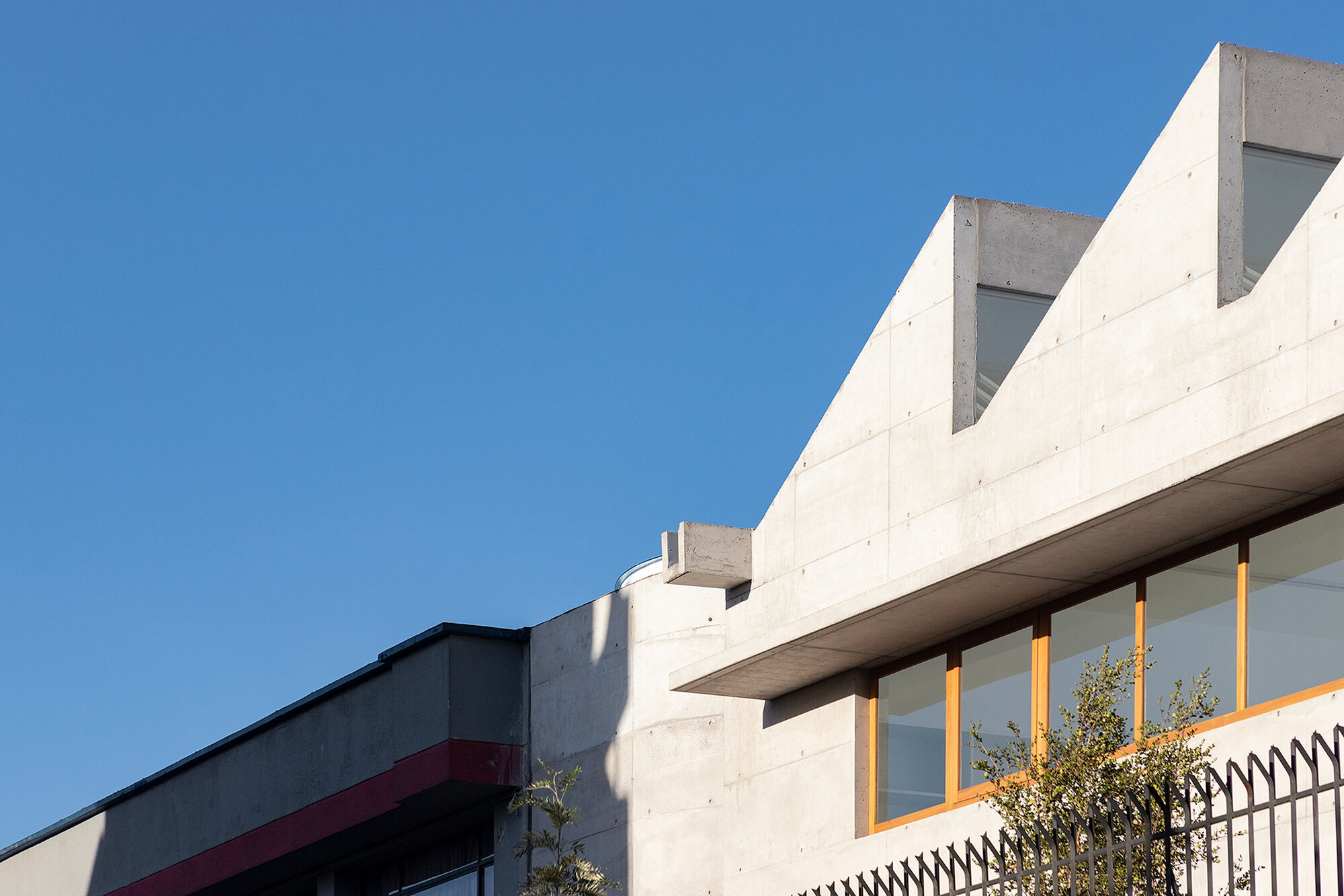 Detail of stepped concrete roofline and cantilevered overhang with timber framed glazing below