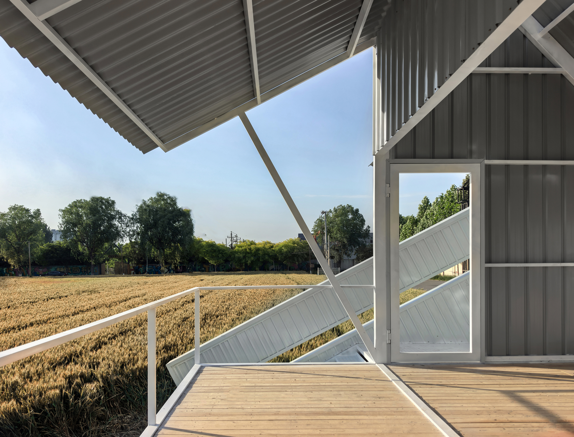 Timber deck platform with white railings framing the wheat field beyond the structure