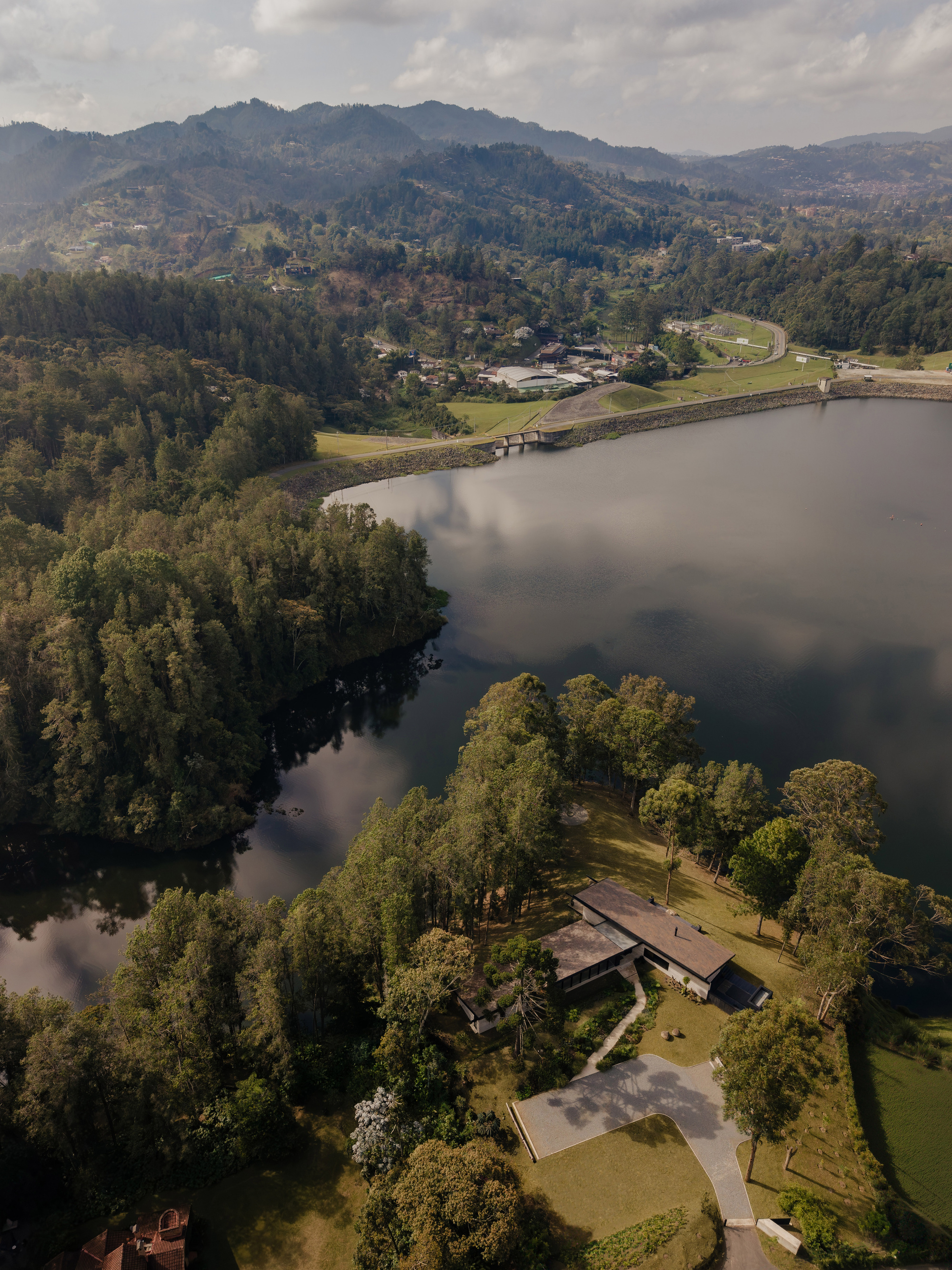 Aerial view of the low-slung residence on a tree-covered peninsula jutting into the reservoir
