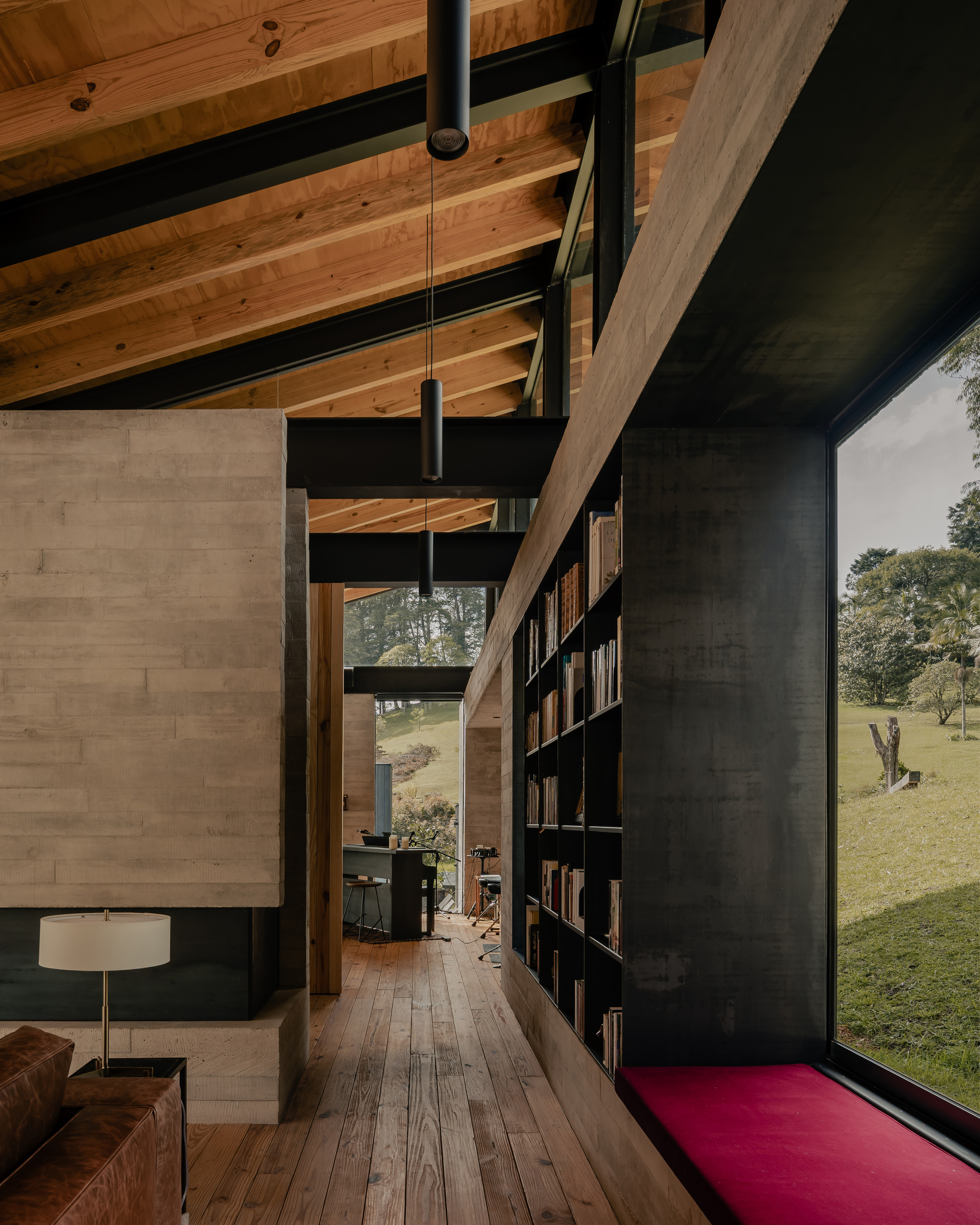 Hallway passage with black steel bookshelf wall and glimpse of the grassy clearing beyond