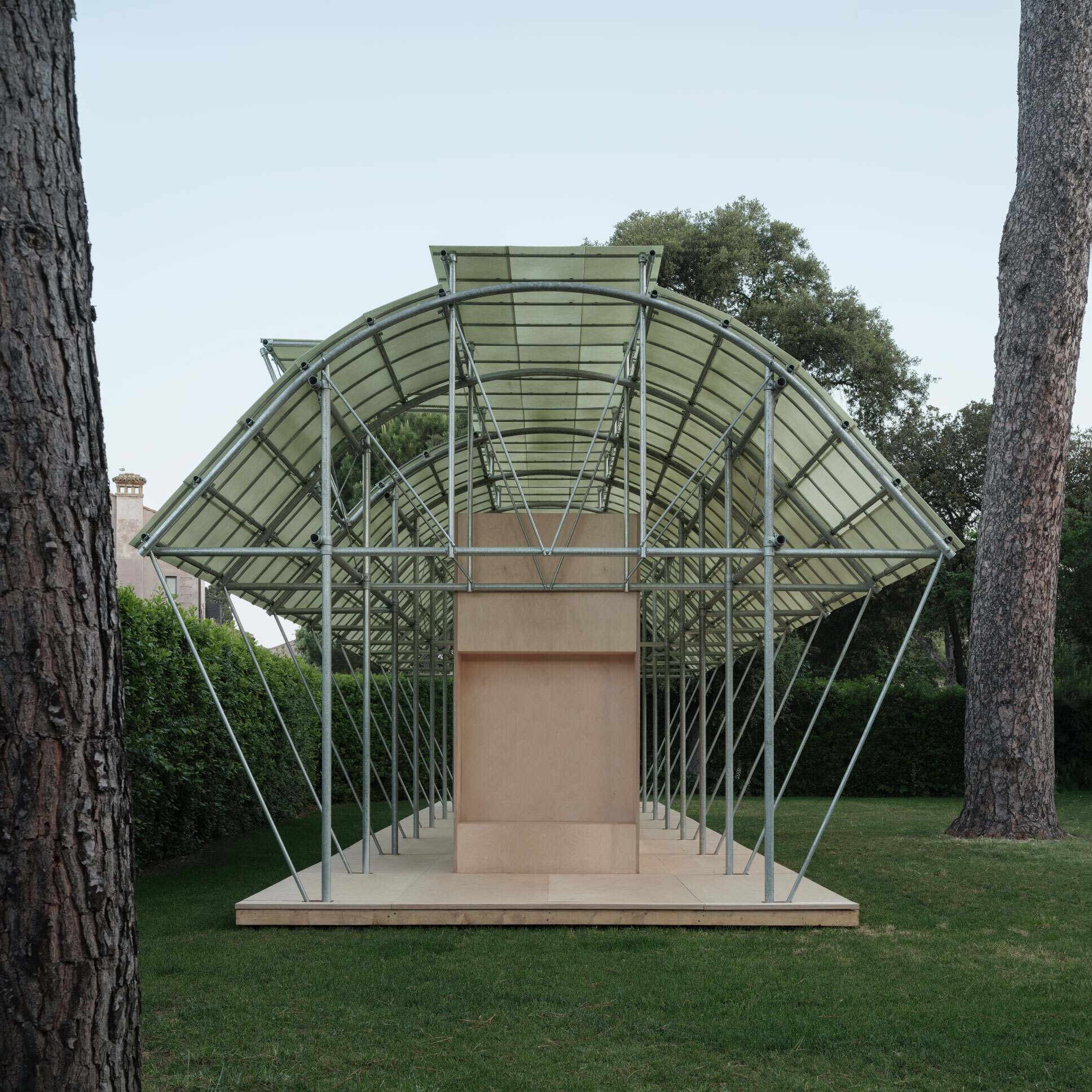 Head-on view of the arched steel structure with glass panels rising above the timber service core