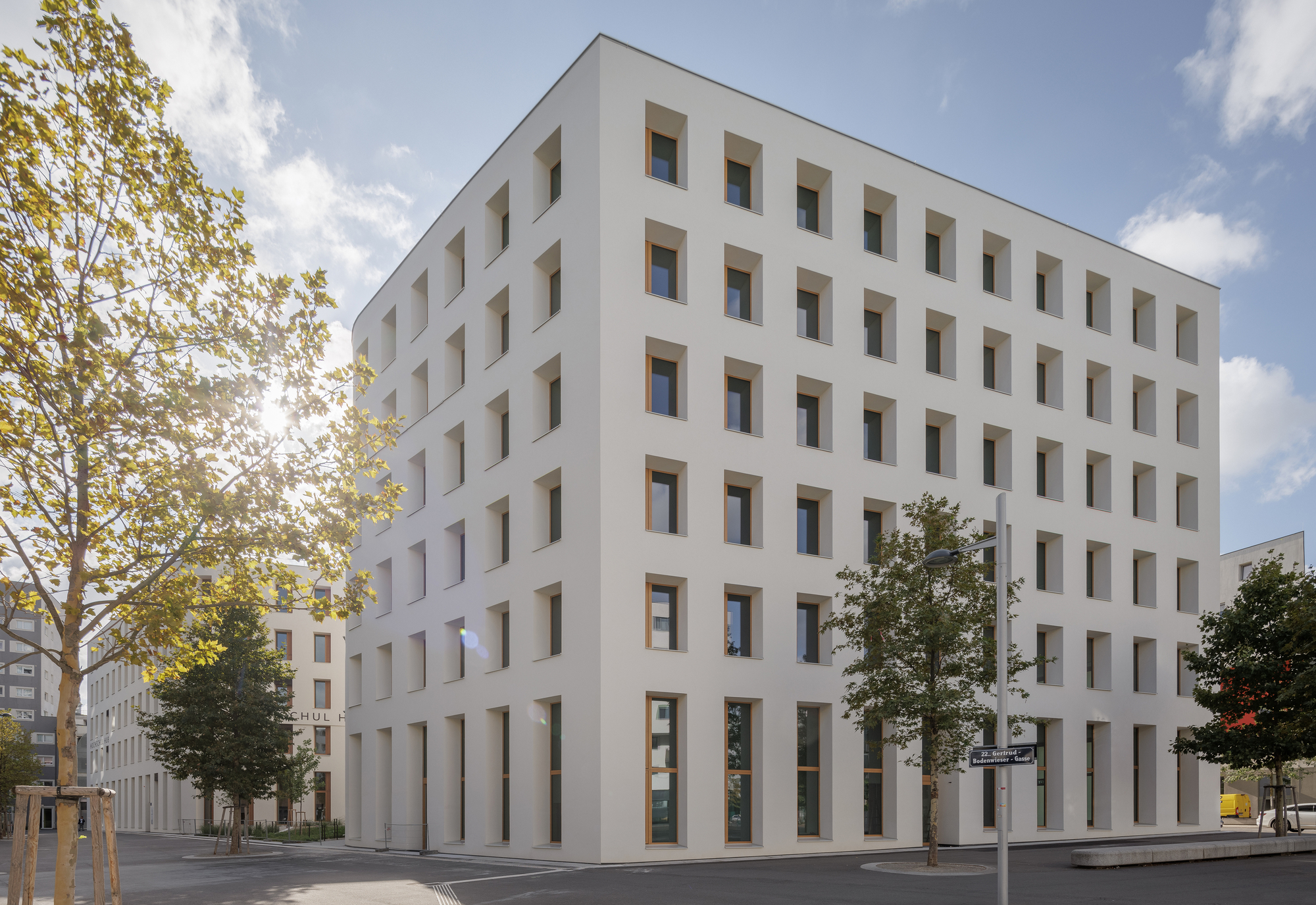 Corner view of the white facade with timber-framed windows and tall ground-floor columns
