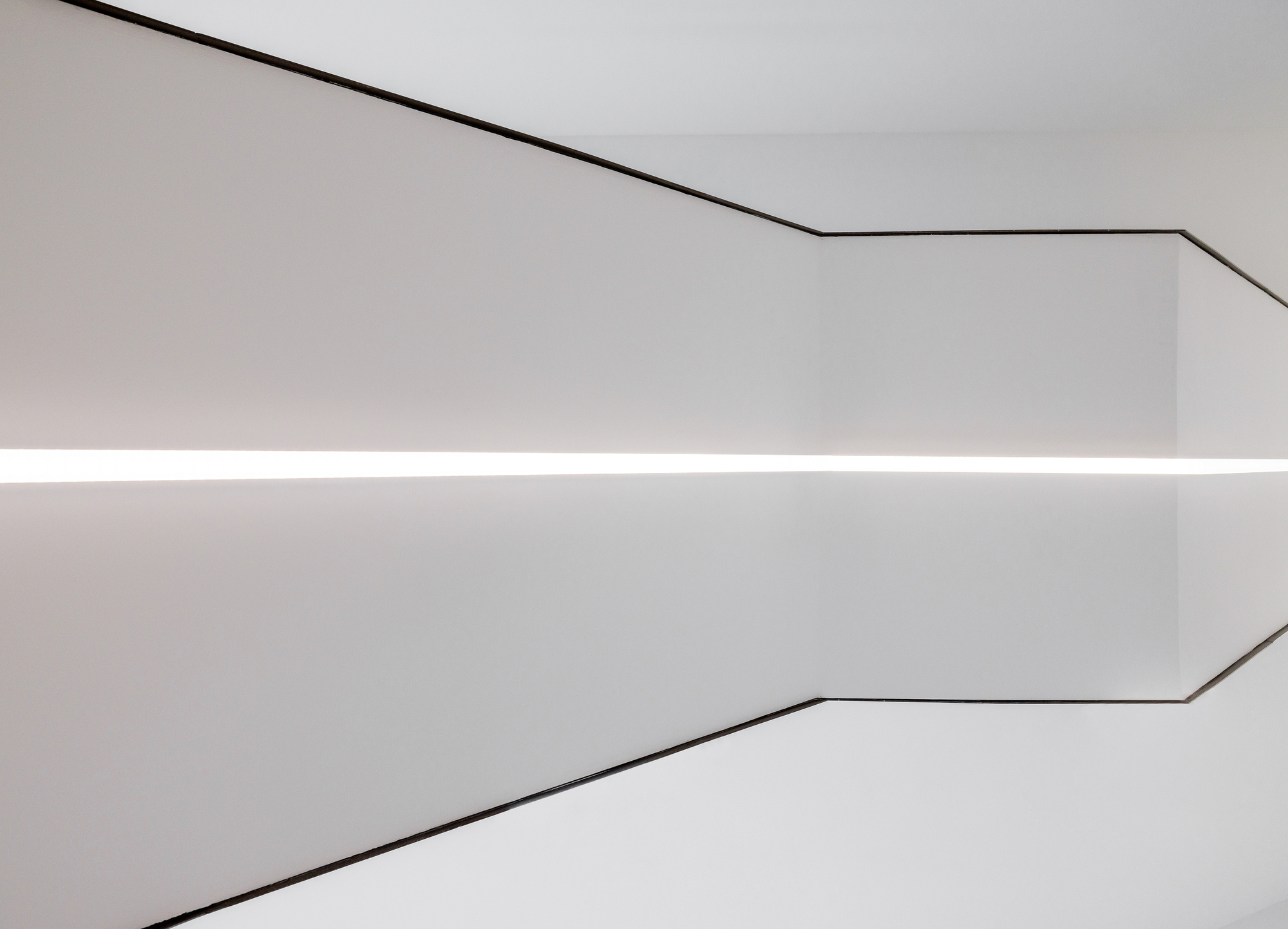 Close-up of a coved ceiling corner with continuous linear lighting and thin metal edge trim