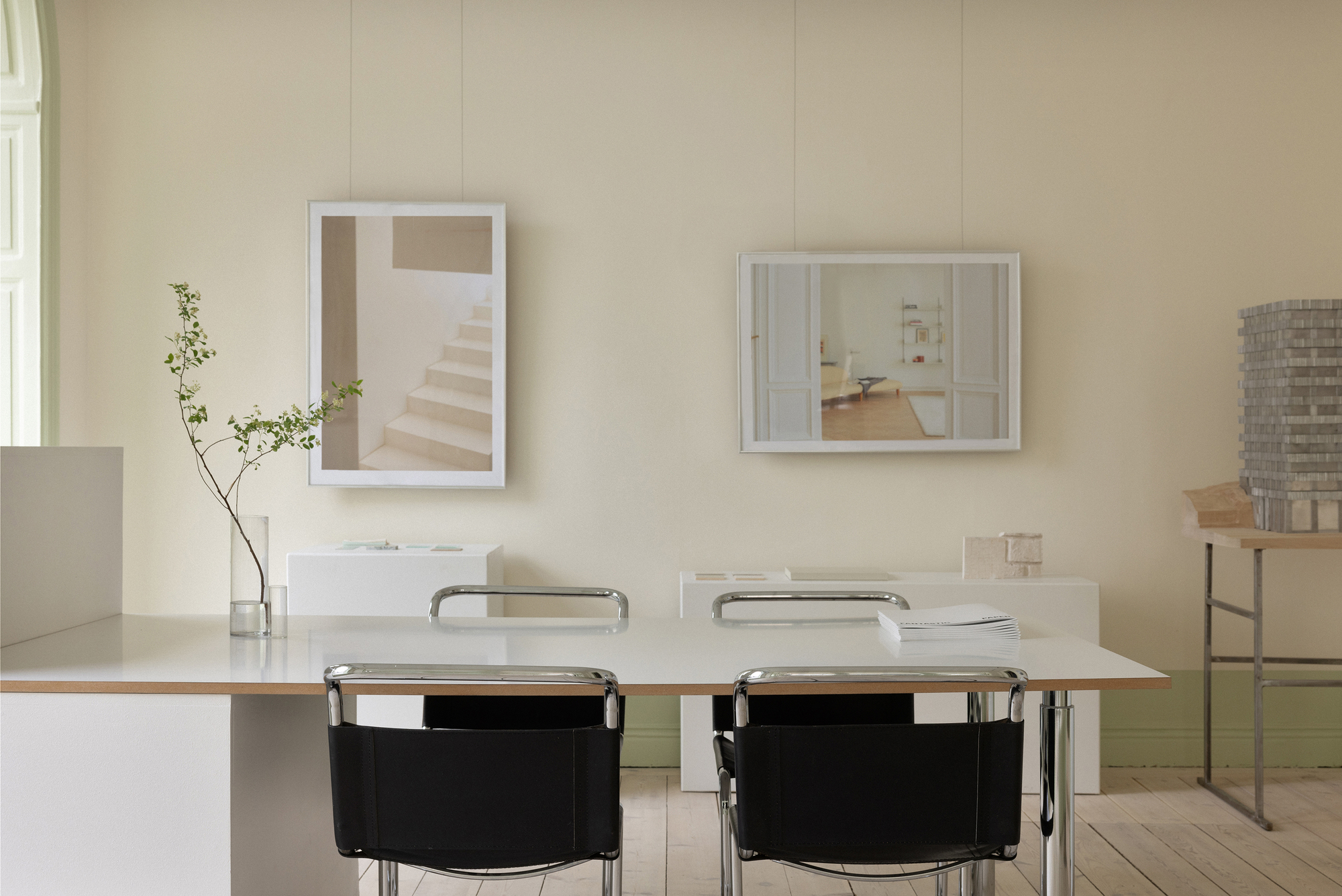 Workspace with table, framed photographs, and an architectural model on the right-hand shelf