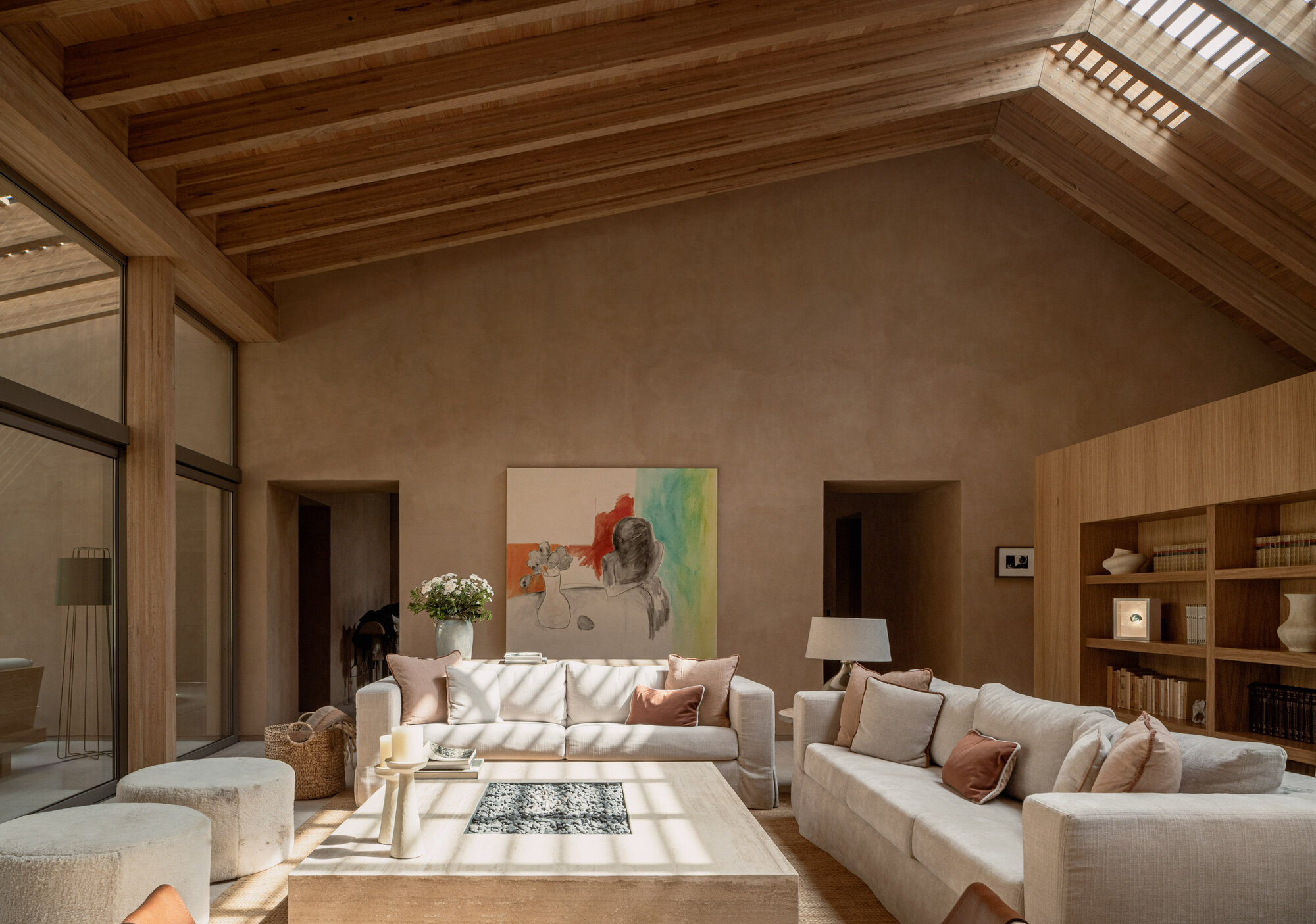 Vaulted ceiling with exposed timber rafters and slatted skylights illuminating a living area below