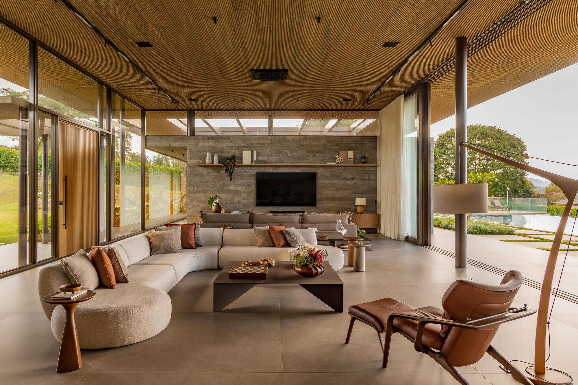 Living room with wood-paneled ceiling and full-height glazing opening to landscaped terrace