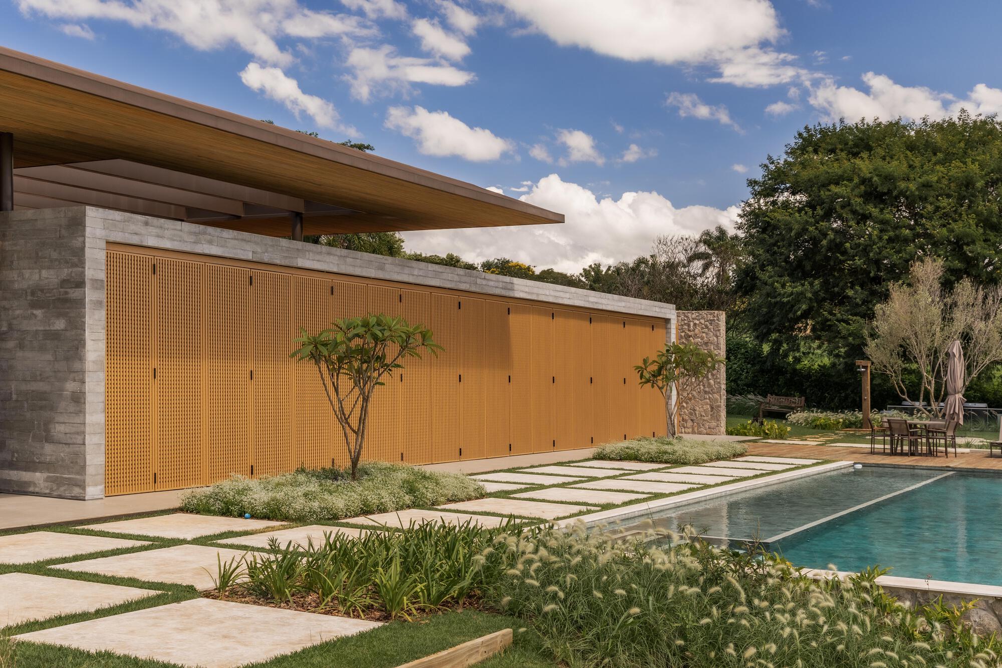 Perforated timber screen wall beside planted beds and limestone pavers along the pool deck