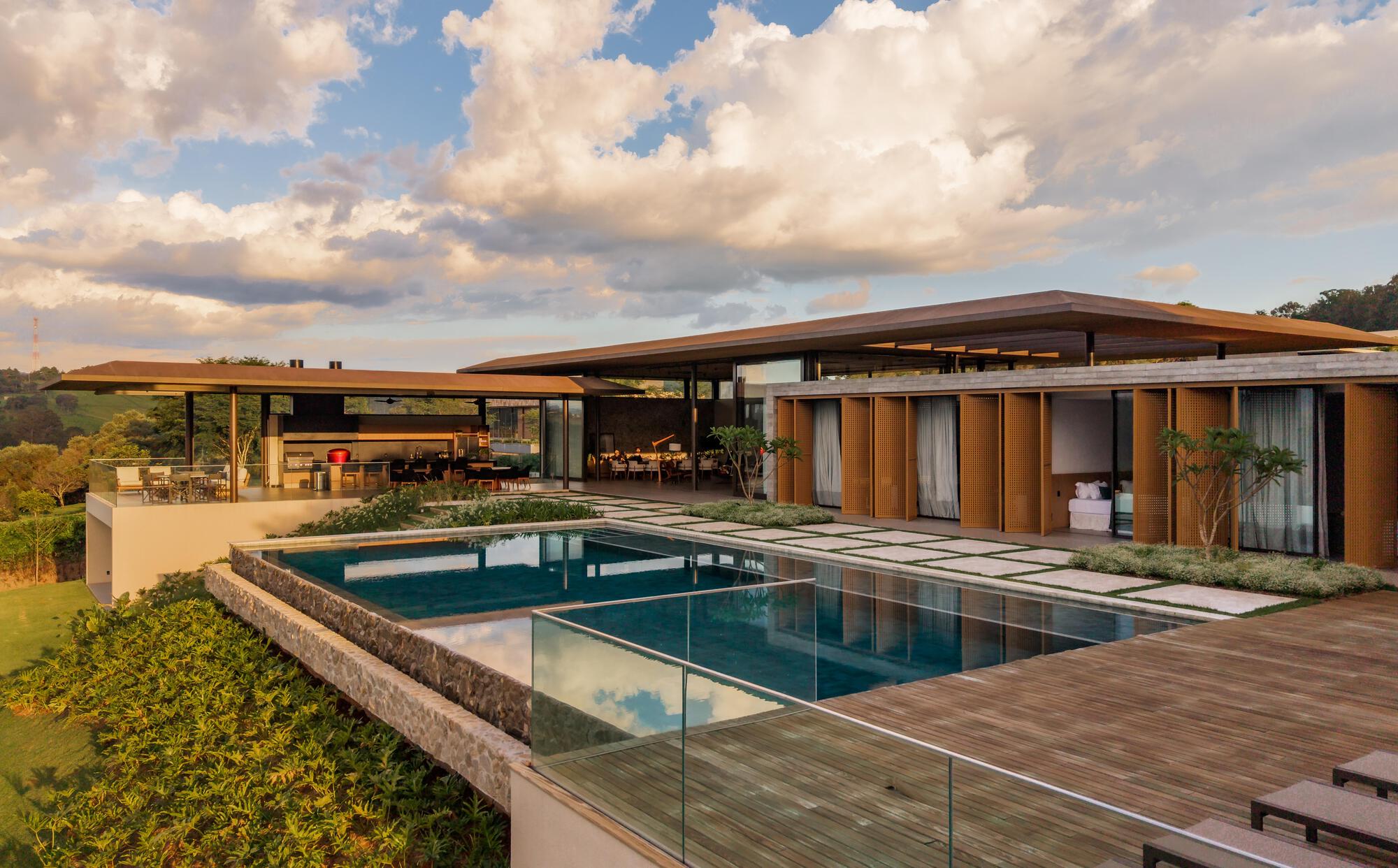 Glass-edged infinity pool and timber deck terrace below the low-slung roof at dusk