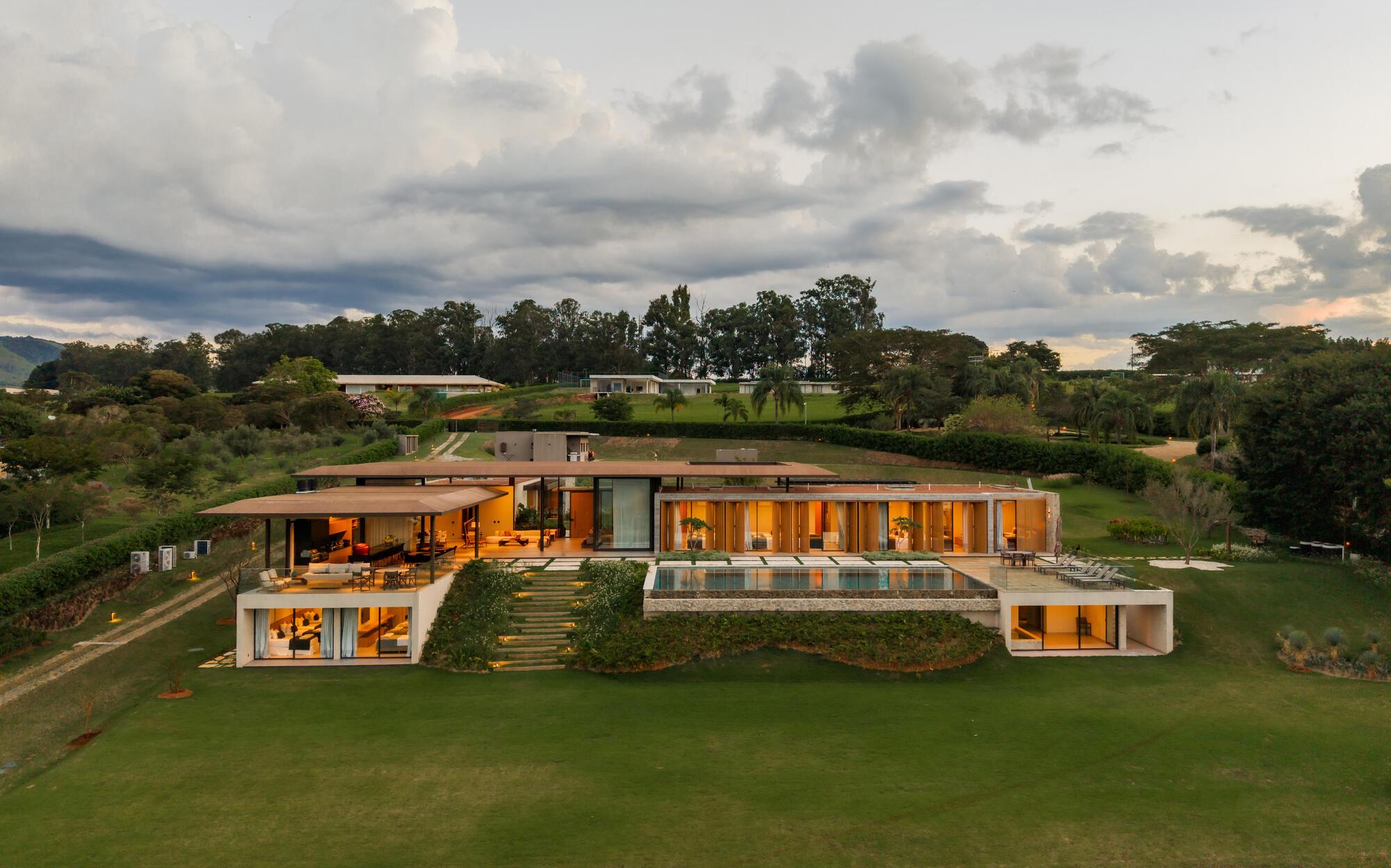 Aerial view of the stepped residence carved into the sloping lawn at twilight