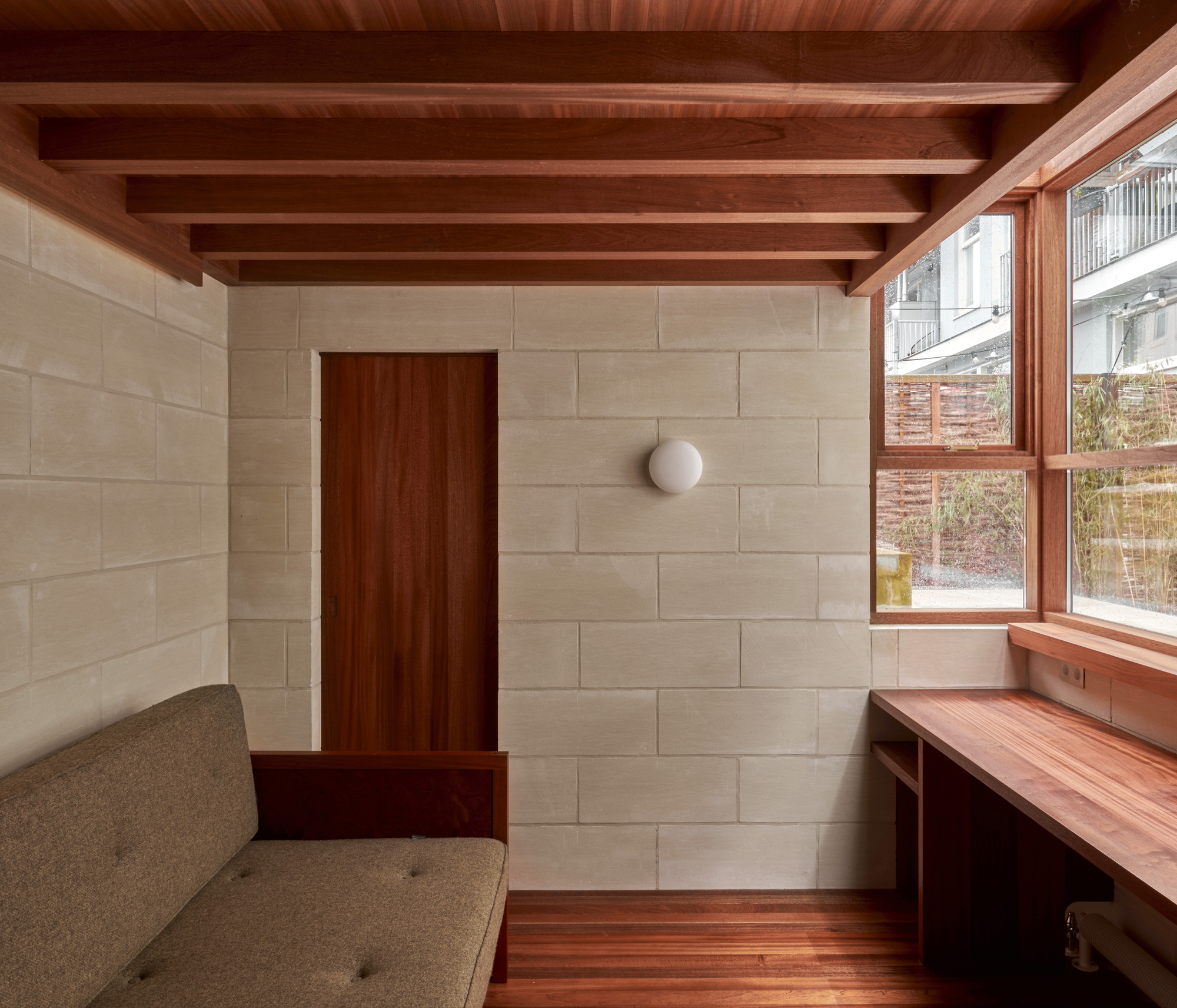Interior room with exposed timber ceiling beams, limestone block walls, and a timber-framed window seat