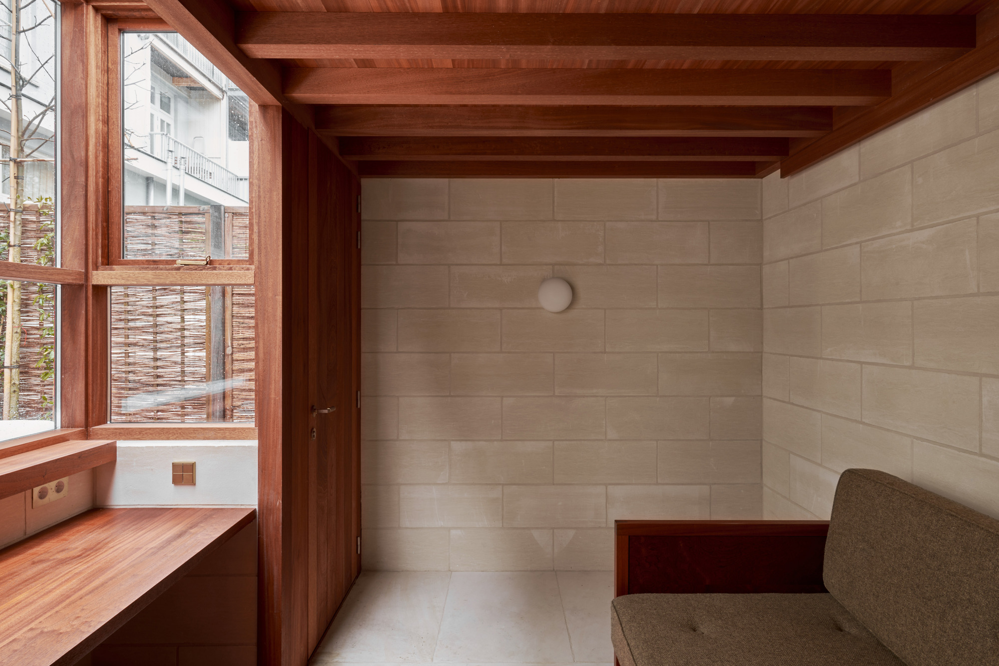 Corner view showing timber door, exposed ceiling joists, and limestone block wall with spherical wall sconce