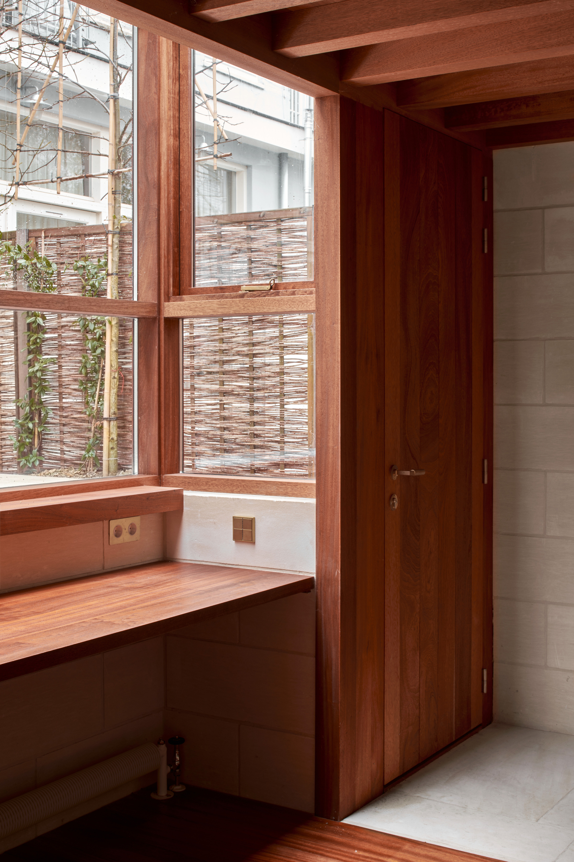 Built-in timber desk beneath corner window framed by exposed ceiling beams and limestone block walls