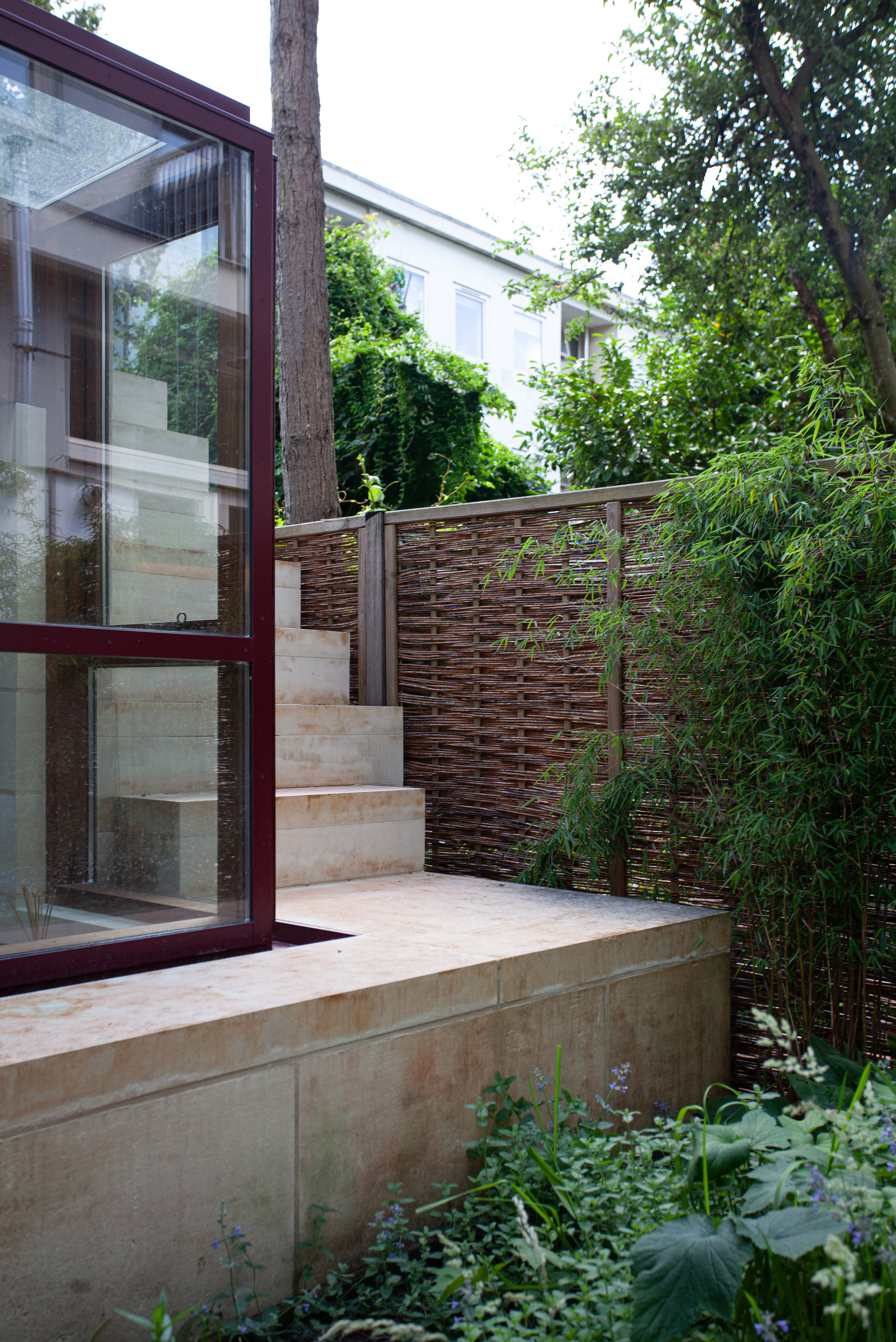 Garden terrace with limestone steps and timber screen fence surrounded by bamboo and tree canopy