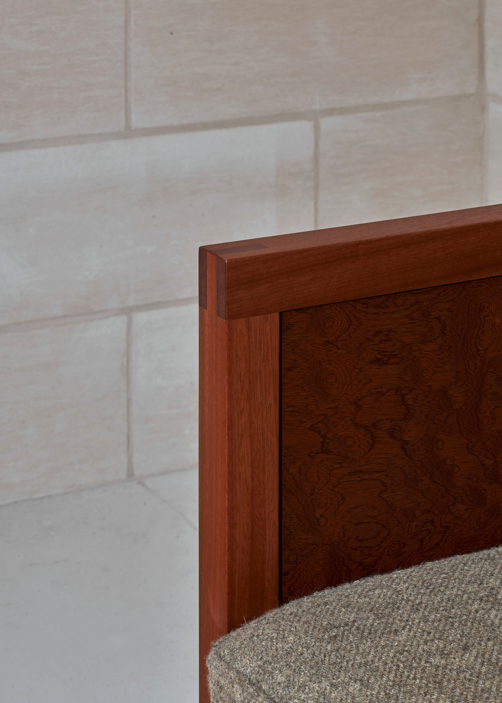 Corner detail of timber joinery against a limestone block wall with woven cushion