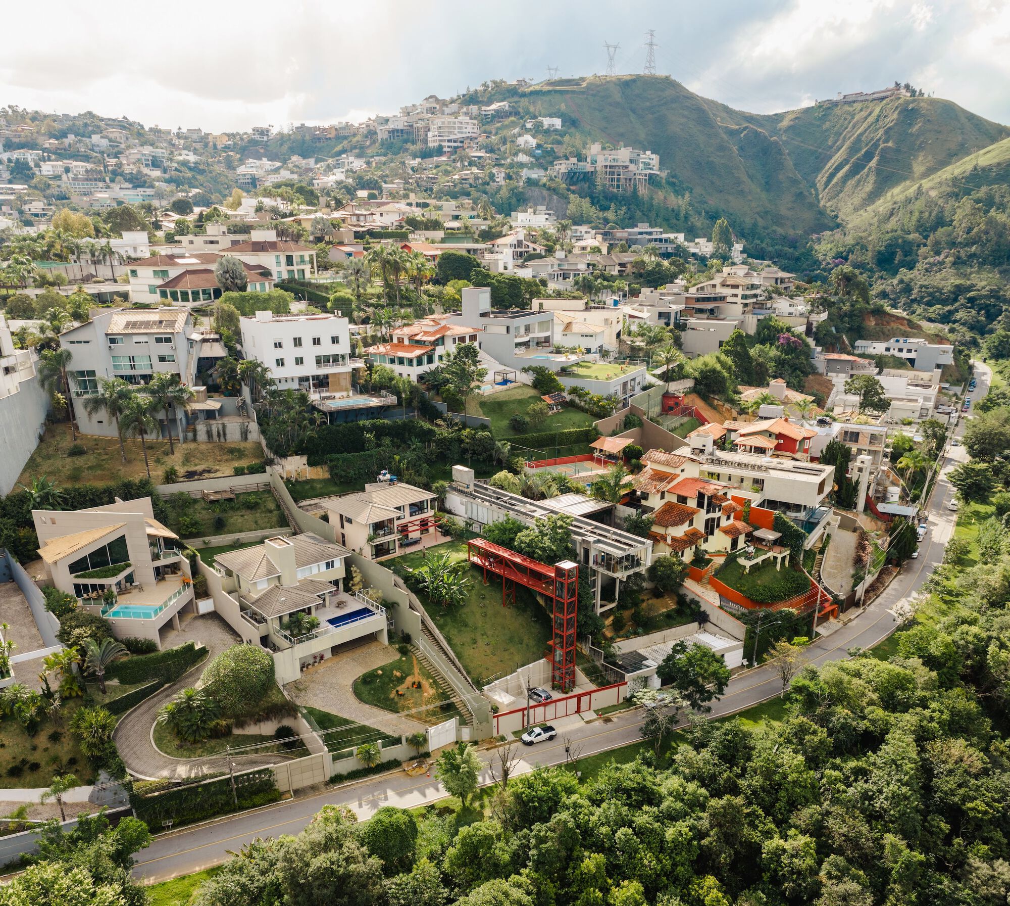 Aerial view of the residence with red steel tower on a hillside neighborhood with mountains behind