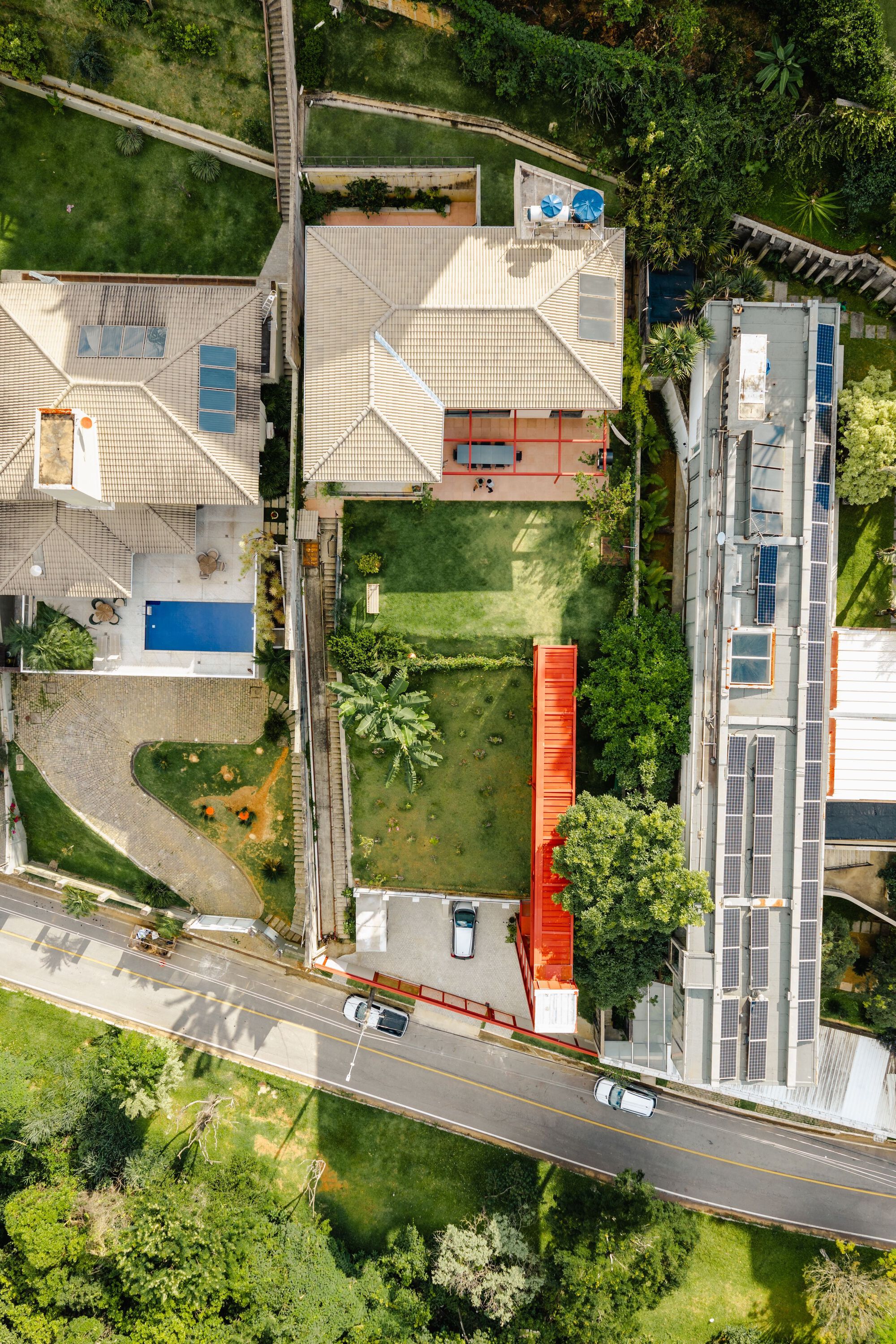 Aerial view of a narrow house with a red steel tower rising along the sloped garden