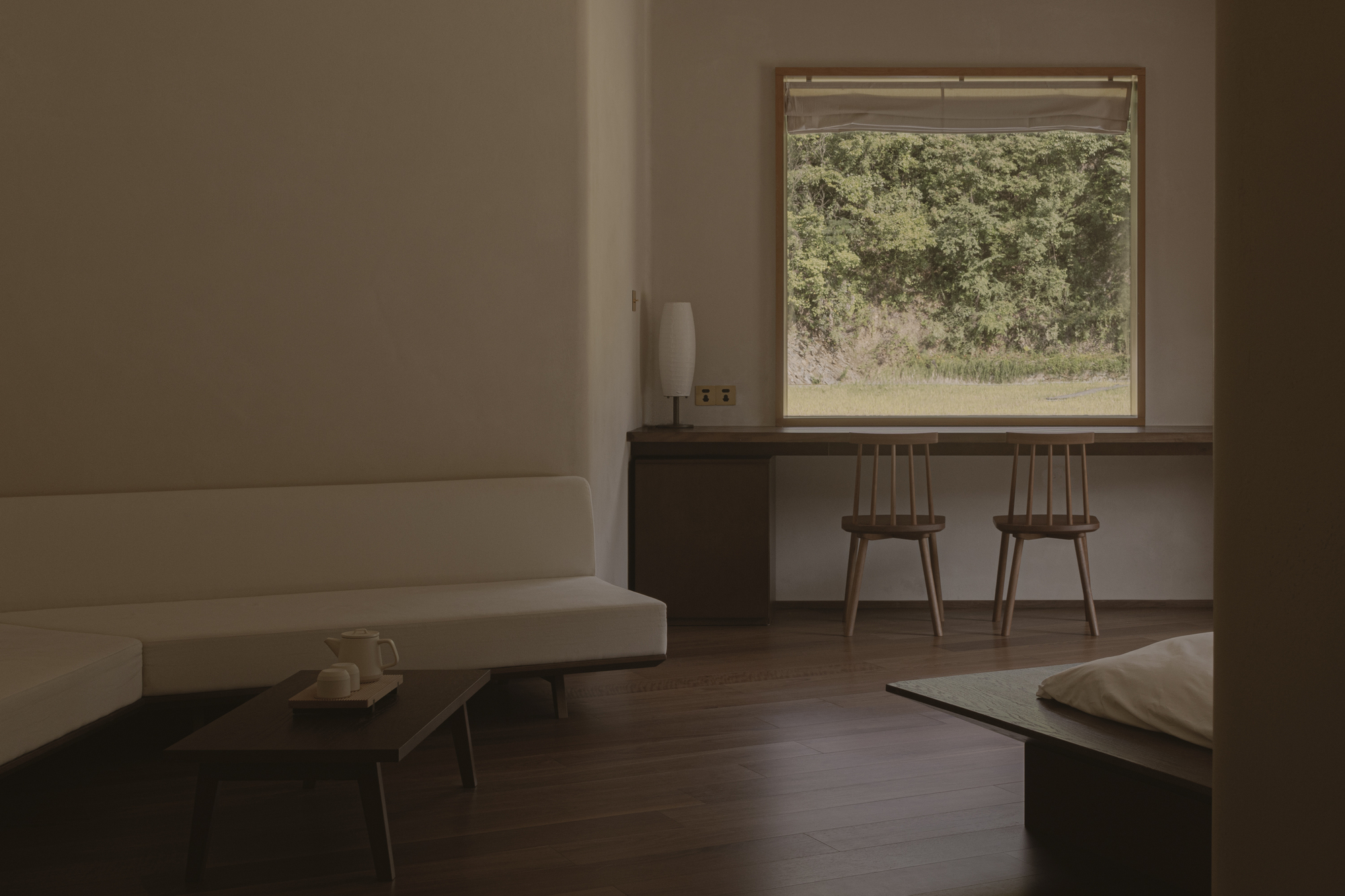 Living area with built-in desk, two wooden chairs and window framing a rocky hillside