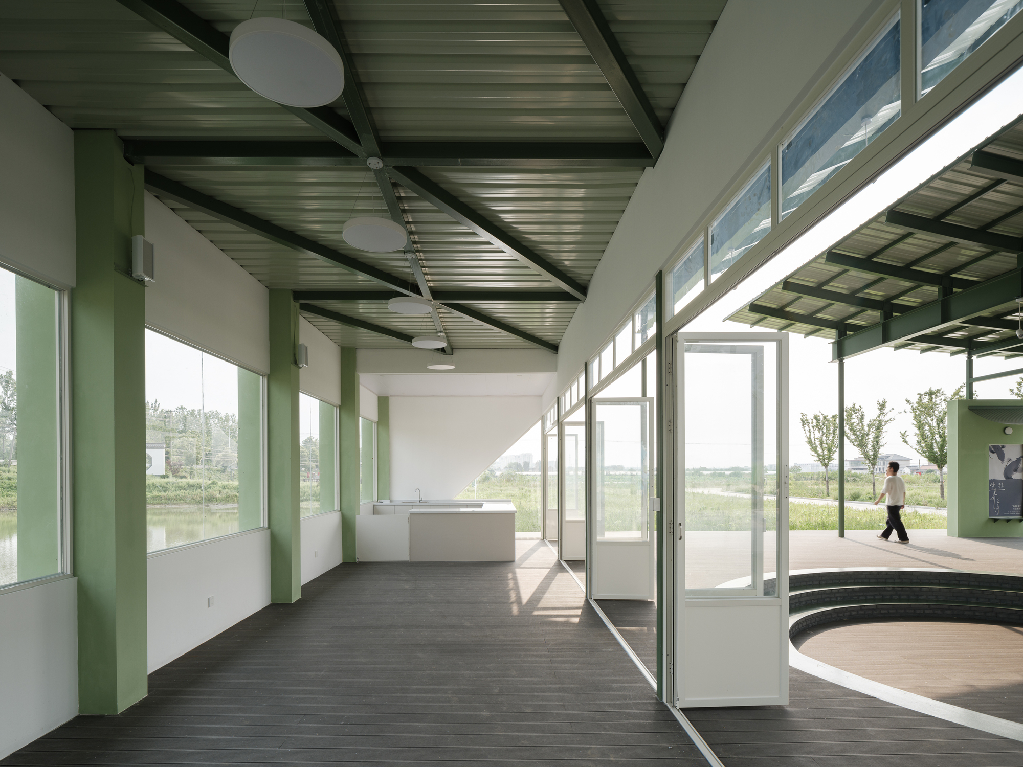 Interior corridor with green columns and clerestory glazing casting afternoon shadows on dark flooring