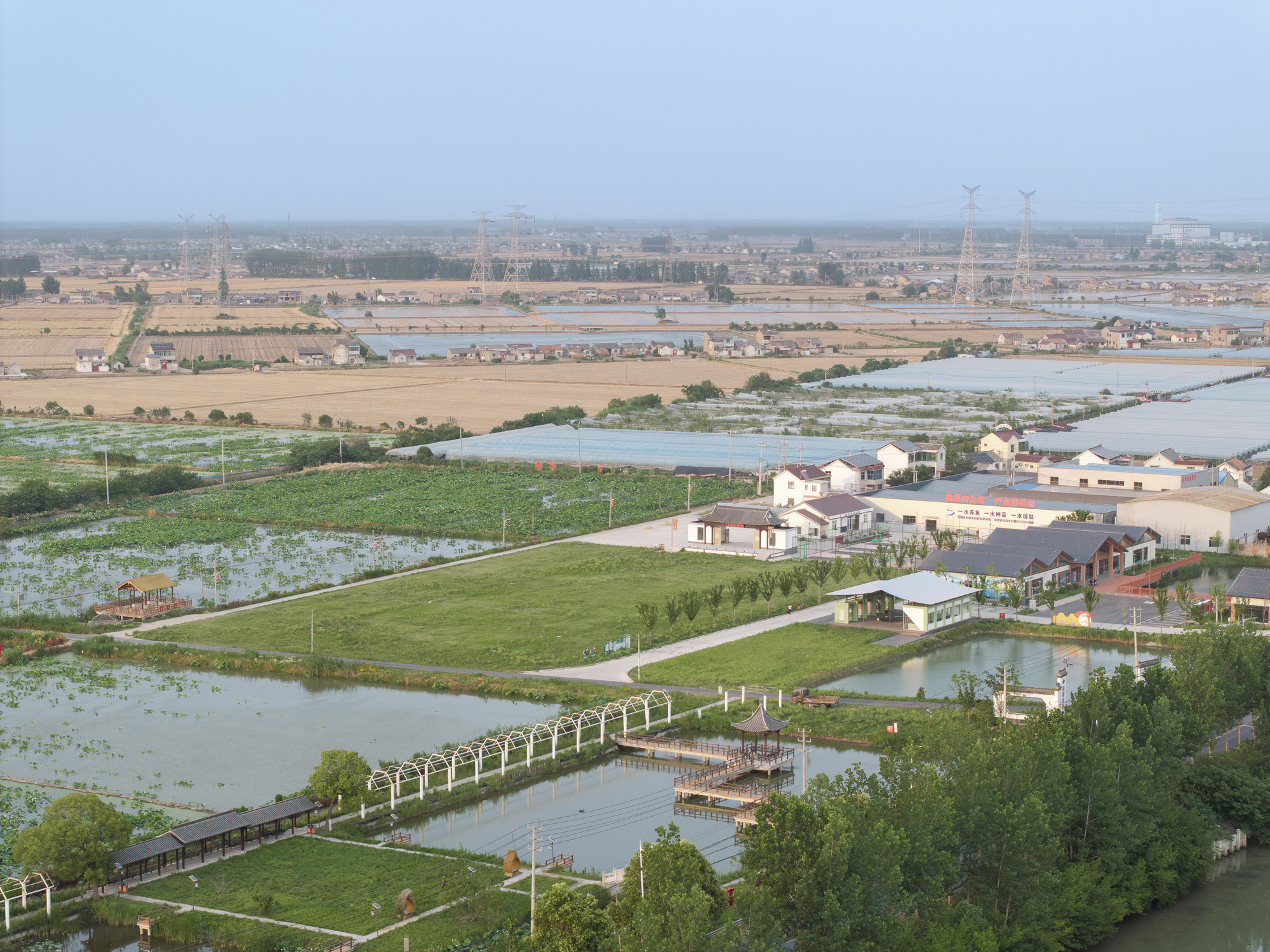 Wide aerial perspective showing the park's curved pathways, water bodies, and scattered residential buildings