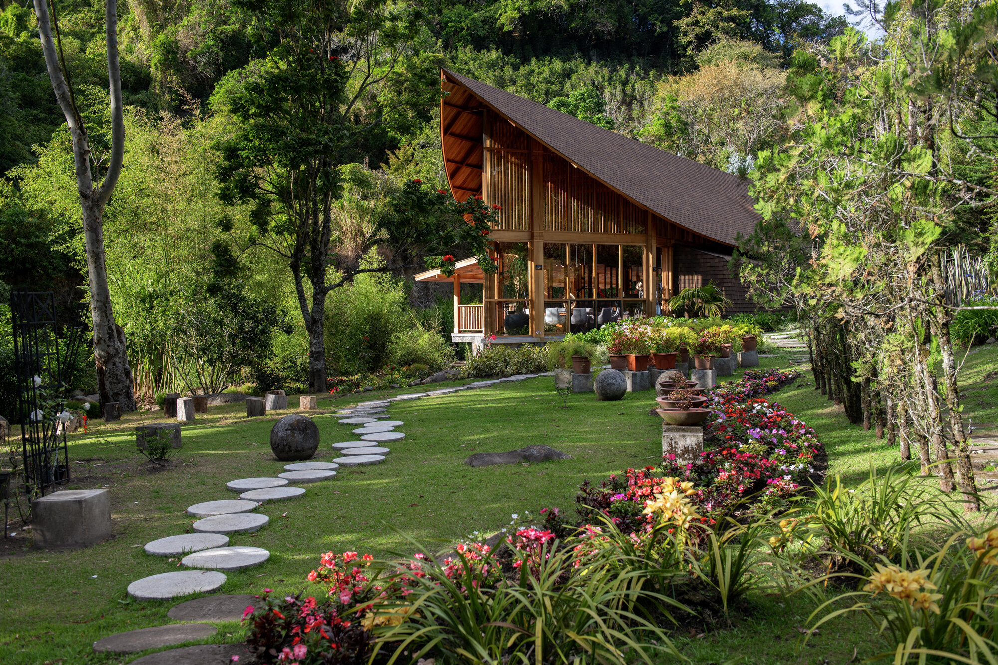 Circular stepping stone path through the lawn leading to the pitched roof residence surrounded by planted beds
