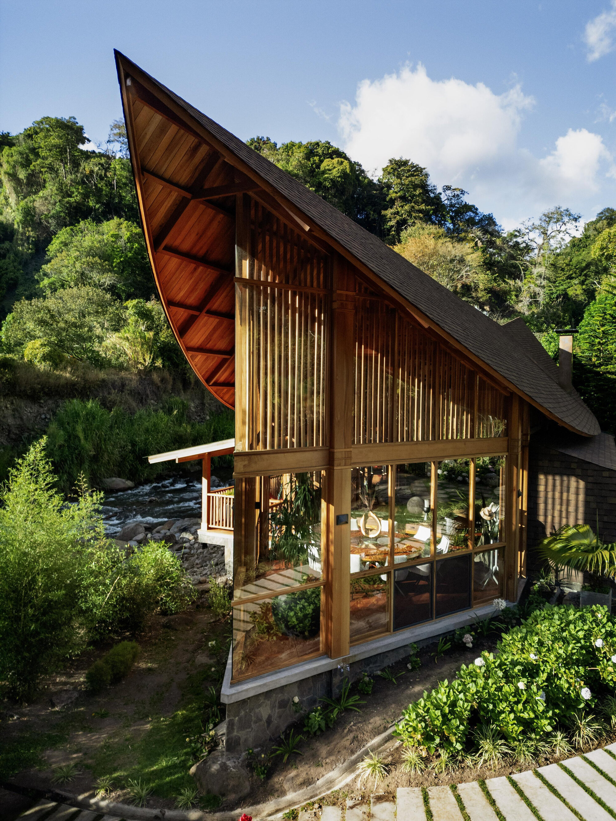Elevated view of the glazed lower level with timber columns beneath the soaring gabled roof