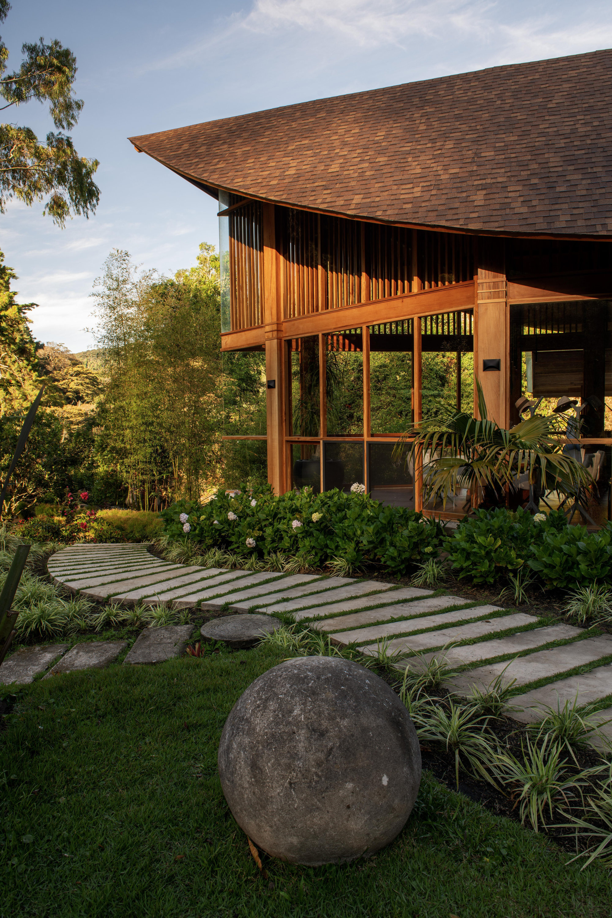Stepping stone path through lawn leading to the timber screened entrance with spherical stone ornament