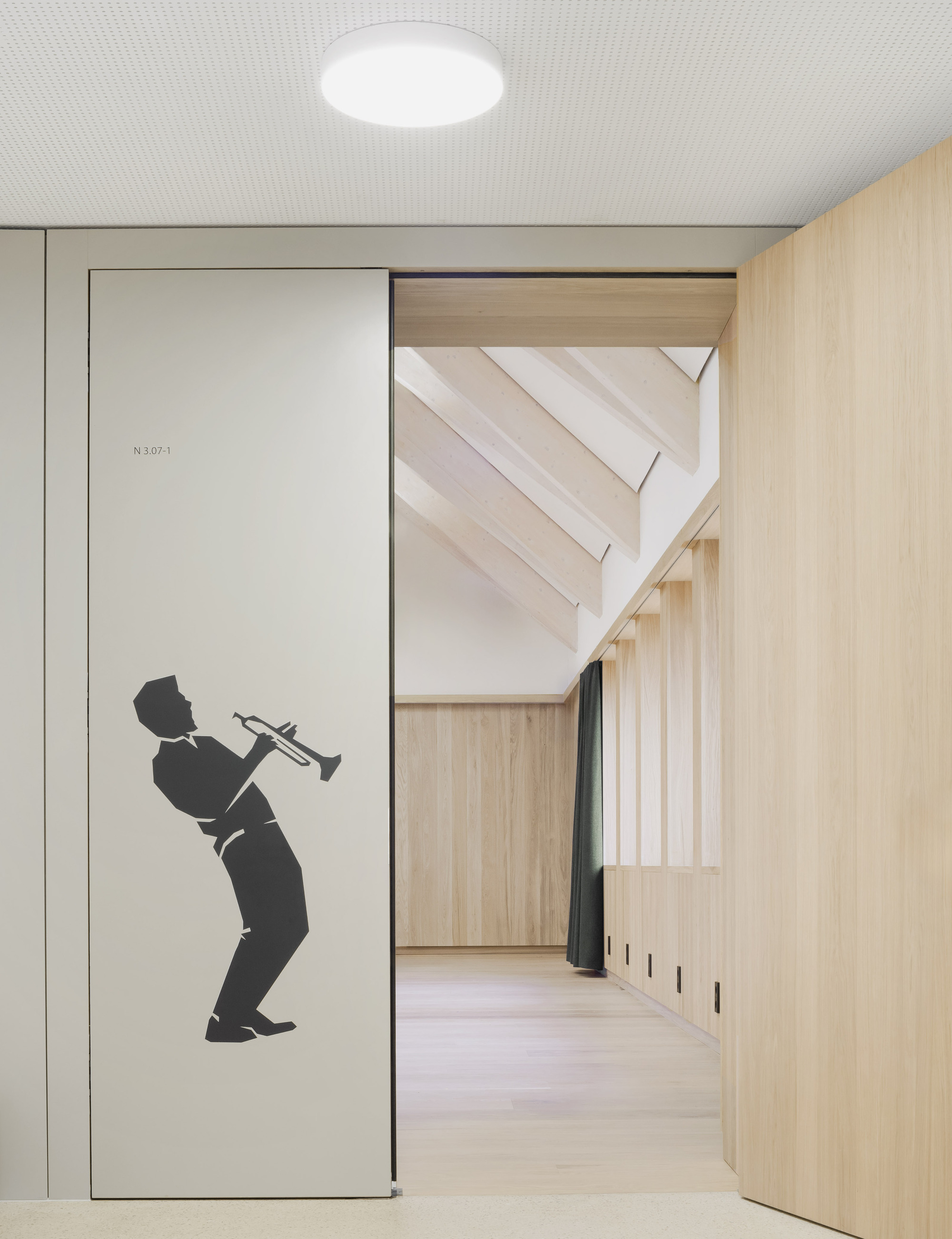 Corridor entrance with silhouette graphic of a trumpeter on a sliding door panel