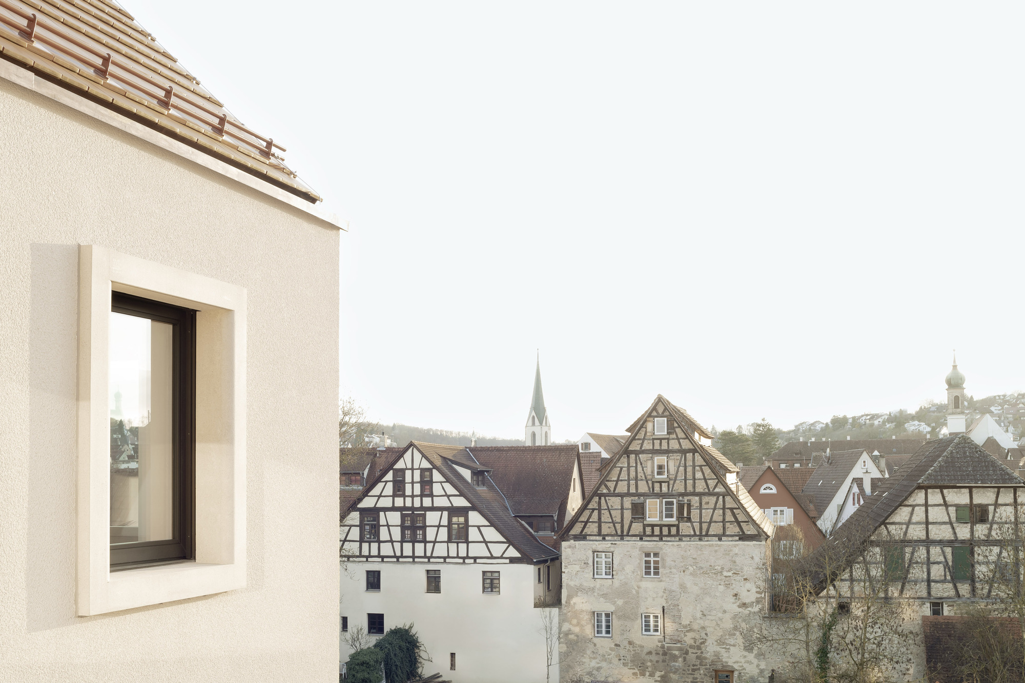 Roof terrace window overlooking a cluster of timber-framed houses and church spires in morning light